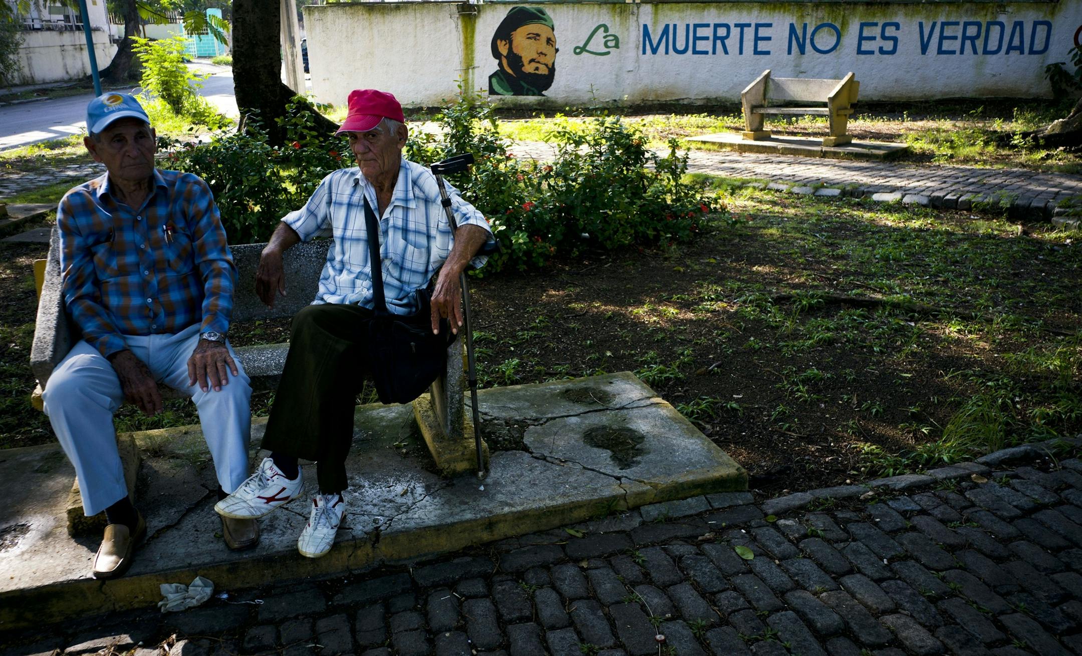 Men sit in a park where a mural of Cuba's late leader Fidel Castro reads in Spanish: "Death is not true" in Havana, Cuba, Friday, Nov. 24, 2017. The first one-year anniversary of Fidel Castro's death will be marked on Saturday, Nov. 25. (AP Photo/Ramon Espinosa)