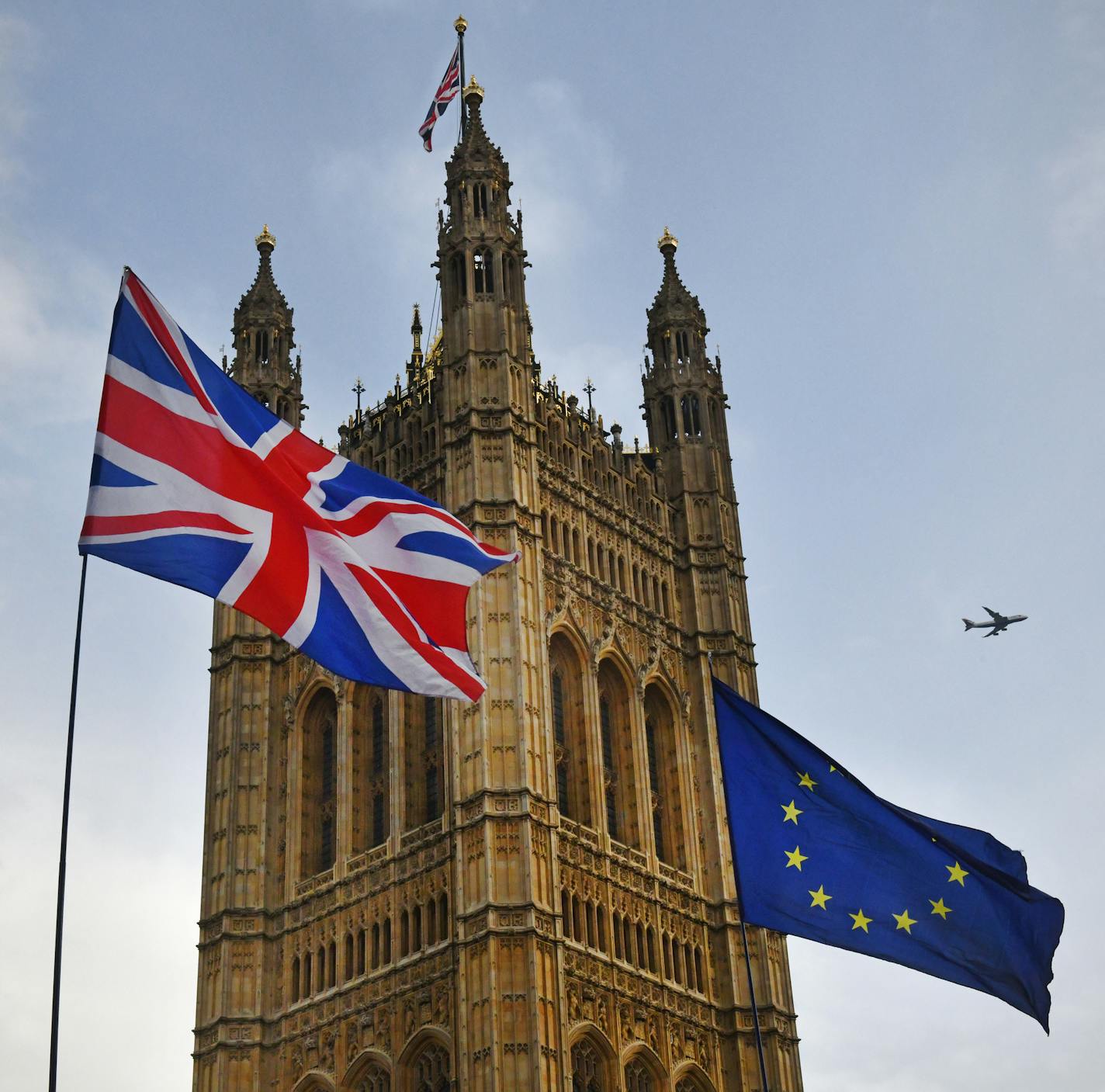 Protesters flags of United Kingdom and European Union outside Parliament in Westminster during the Brexit debates. A British Airways flight passes overhead