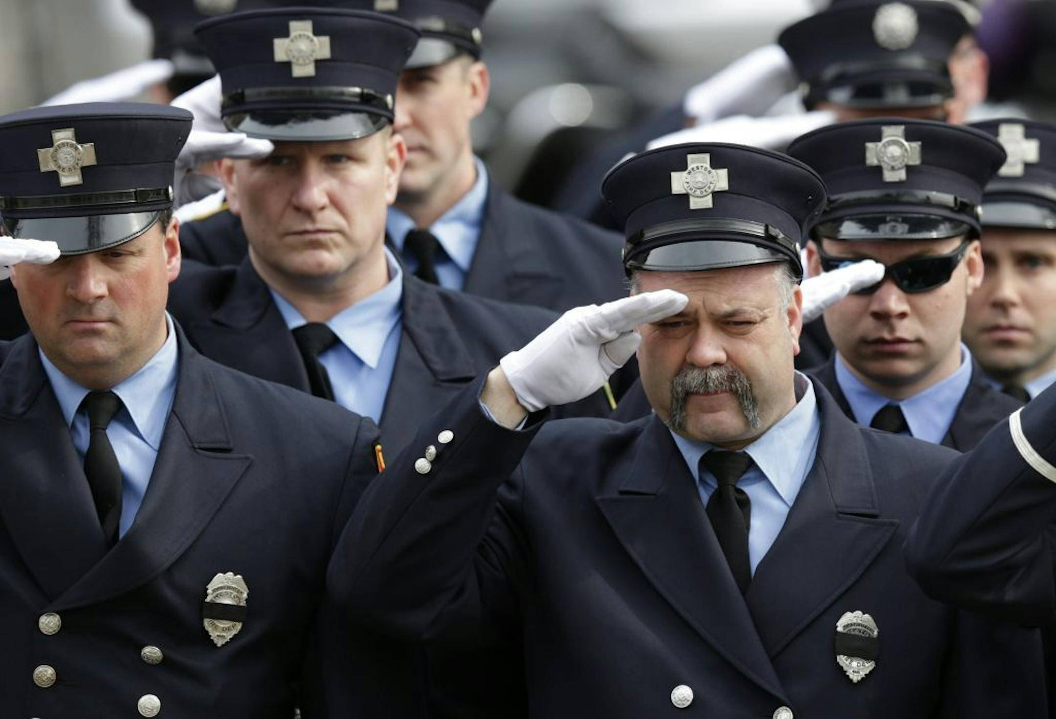 Firefighters salute as the funeral procession of Boston Fire Lt. Edward Walsh arrives outside the Church of Saint Patrick in Watertown, Mass., Wednesday, April 2, 2014.