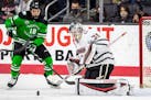 North Dakota's Collins Adams watches a the puck roll in front of Omaha goalie Isaiah Saville during the first period of a college hockey game Friday, 