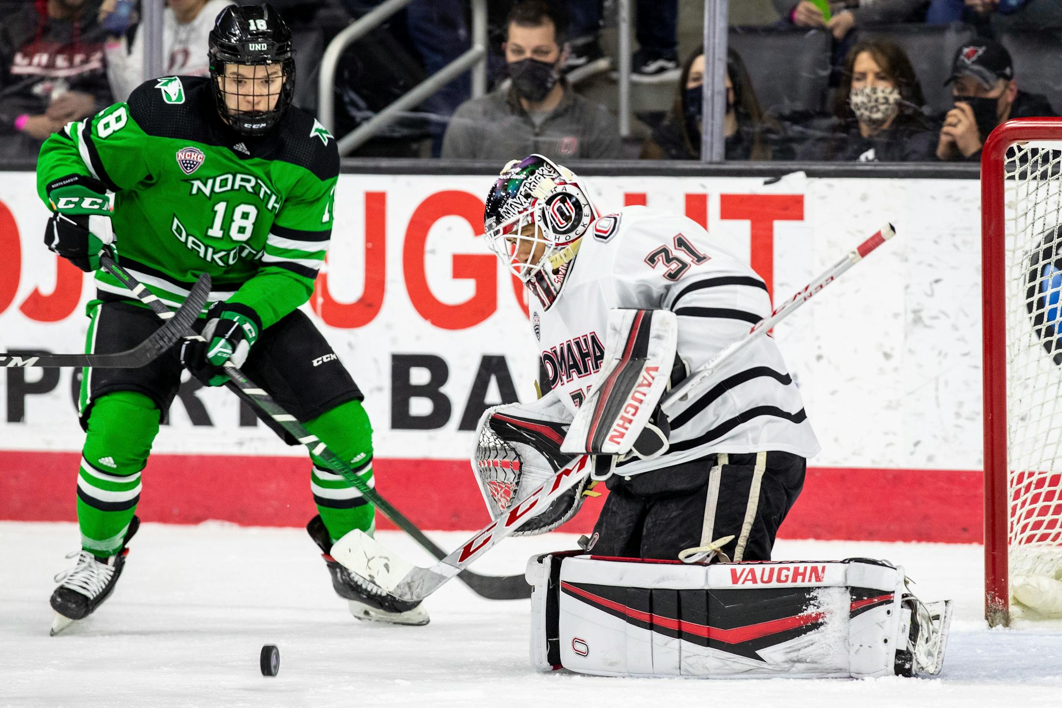 North Dakota's Collins Adams watches a the puck roll in front of Omaha goalie Isaiah Saville during the first period of a college hockey game Friday, Feb. 26, 2021. (Chris Machian/Omaha World-Herald via AP)