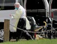 A North Memorial transport worker held a bottle of disinfectant outside North Ridge Health and Rehabilitation where at least 30 residents have died an
