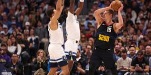 Minnesota Timberwolves forward Kyle Anderson, left, and center Naz Reid defend as Denver Nuggets Nikola Jokic (15) looks to pass during the first quar
