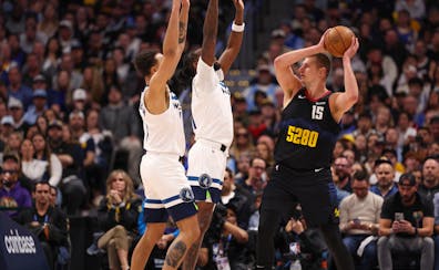 Minnesota Timberwolves forward Kyle Anderson, left, and center Naz Reid defend as Denver Nuggets Nikola Jokic (15) looks to pass during the first quar