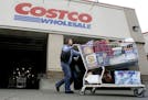 FILE - In this Dec. 7, 2011 file photo, a shopper leaves a Costco store in Portland, Ore.