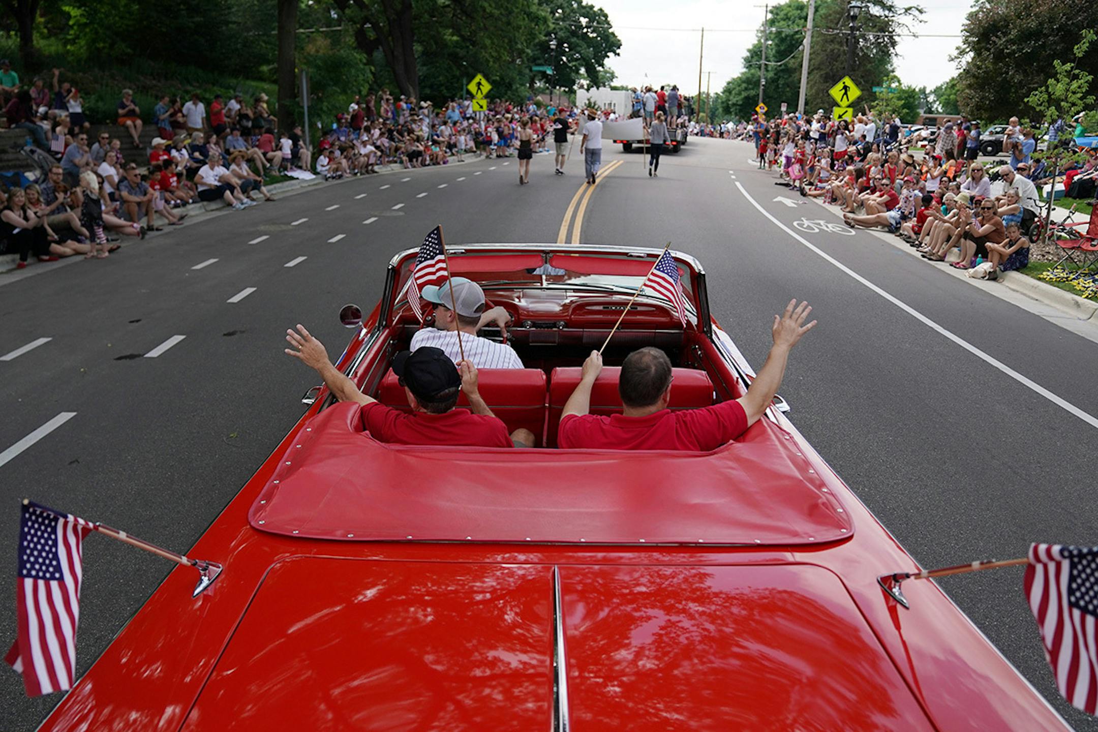 A trio in a red convertible decked out with American flags waved to spectators as they drove the parade route on Thursday, July 4, 2019 in The St. Anthony Park neighborhood of St. Paul.