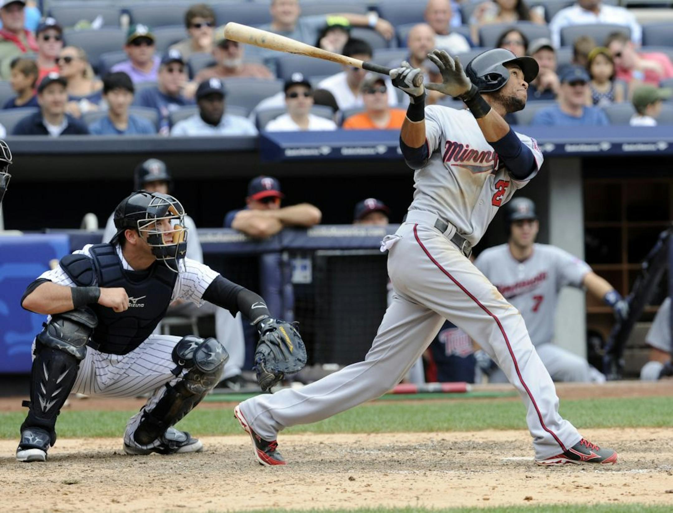 Minnesota Twins' Pedro Florimon follows through on a two-run home run as New York Yankees catcher Austin Romine, left, looks on during the eighth inning of a baseball game Saturday, July 13, 2013, at Yankee Stadium in New York.