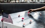 A woman places flowers during a ceremony at the 9/11 Memorial in lower Manhattan on Thursday, Sept. 11, 2019, the 18th anniversary of the Sept. 11 ter