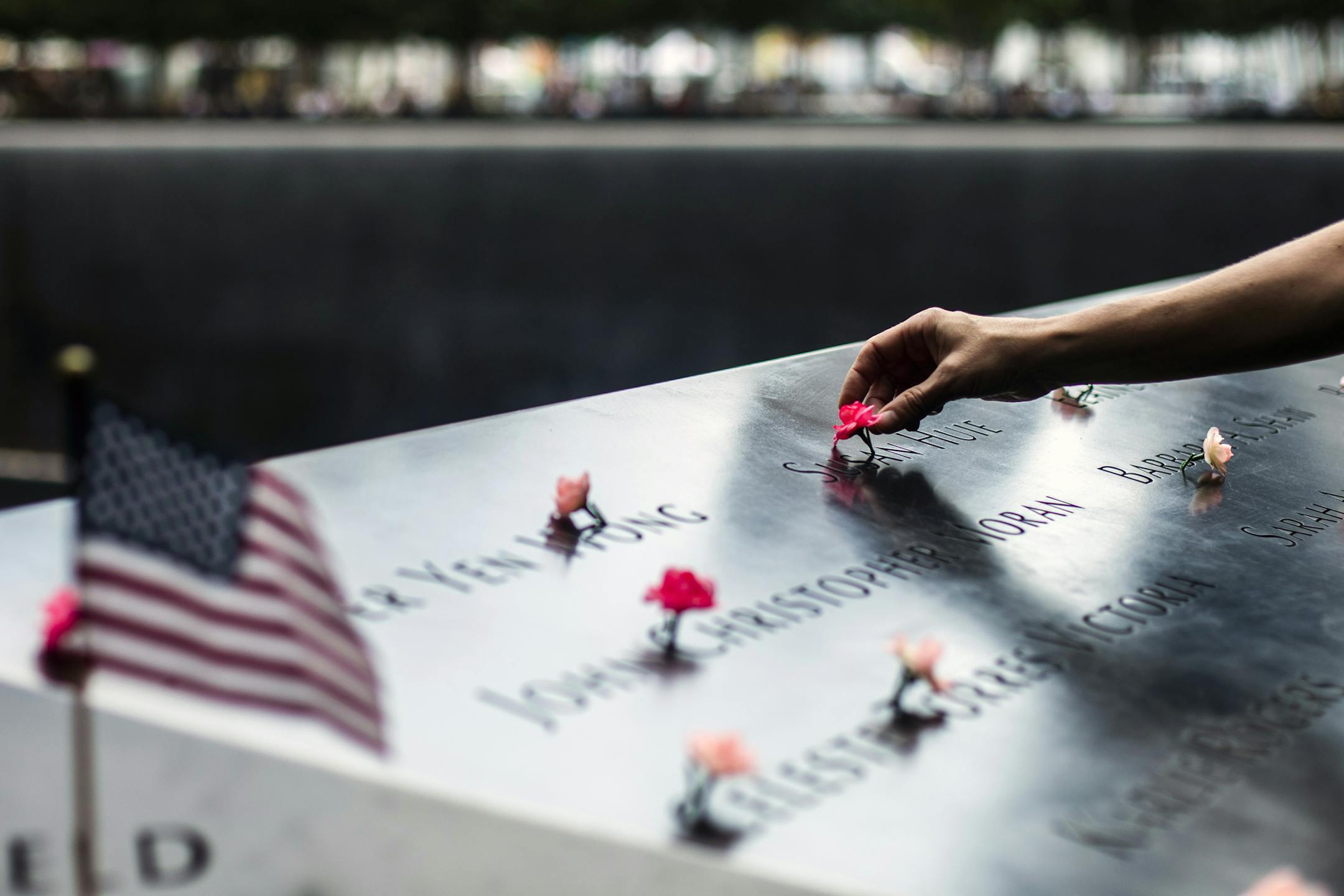 A woman places flowers during a ceremony at the 9/11 Memorial in lower Manhattan on Thursday, Sept. 11, 2019, the 18th anniversary of the Sept. 11 terror attacks. (Brittainy Newman/The New York Times)