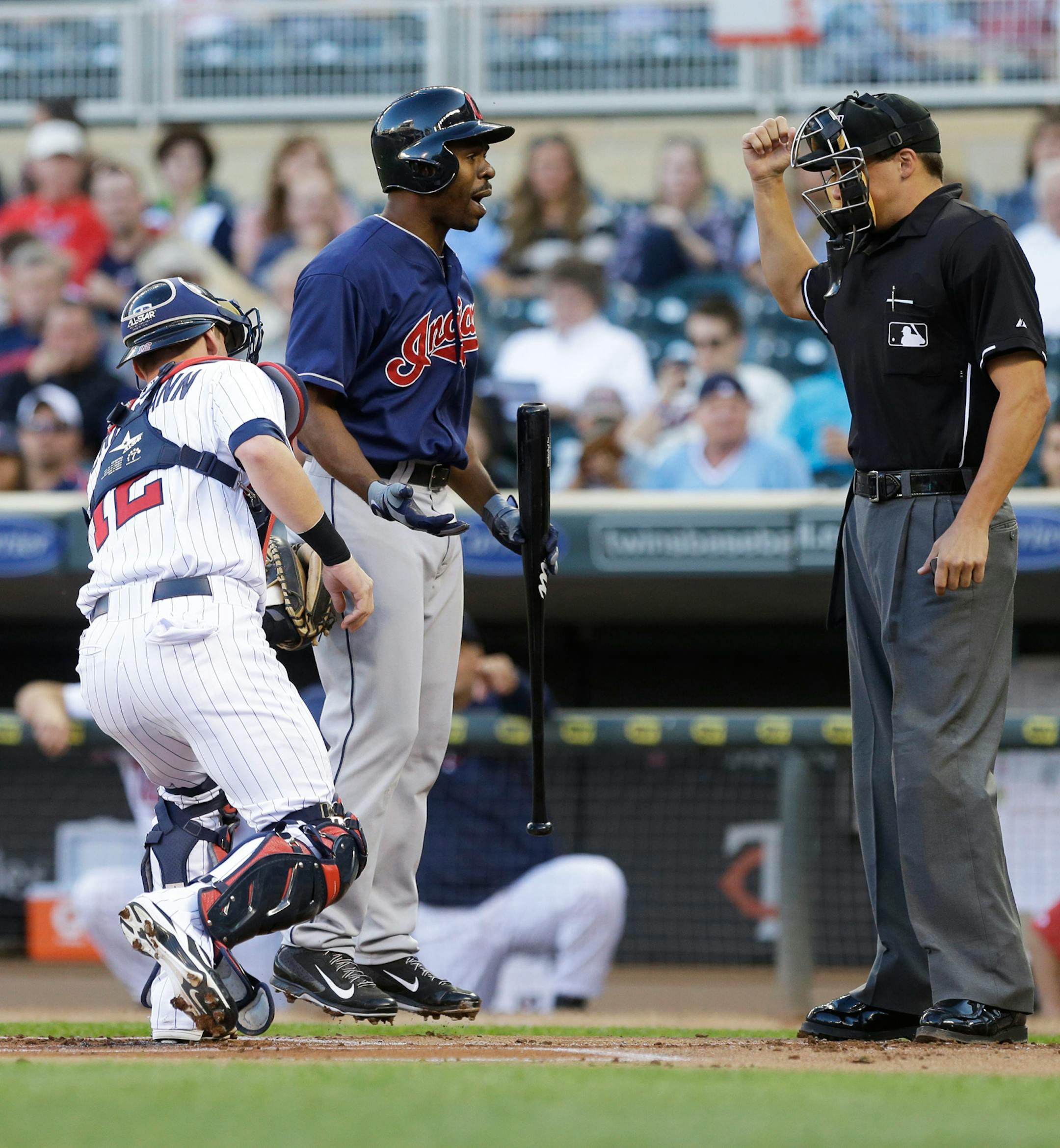 Cleveland Indians' Michael Bourn leaves the ground as he disputes a strikeout call by plate umpire Adam Hamari, right, as Minnesota Twins catcher Chris Herrmann makes the tag in the first inning of a baseball game, Tuesday, Aug. 13, 2013 in Minneapolis. (AP Photo/Jim Mone)