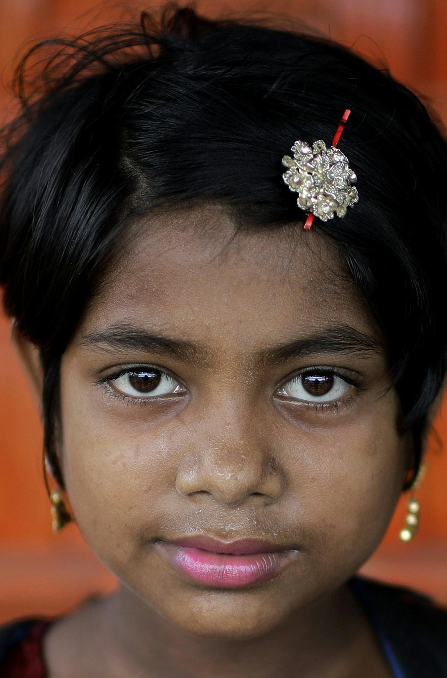 In this June 27, 2018, photo, Nazifa, 10, poses for a portrait in front of her classroom in Chakmarkul refugee camp, Bangladesh. Amid the misery and mud of Bangladesh&#xed;s refugee camps, Rohingya girls have found small moments of joy by adorning themselves with flowery headbands and elaborately-drawn makeup. (AP Photo/Wong Maye-E)