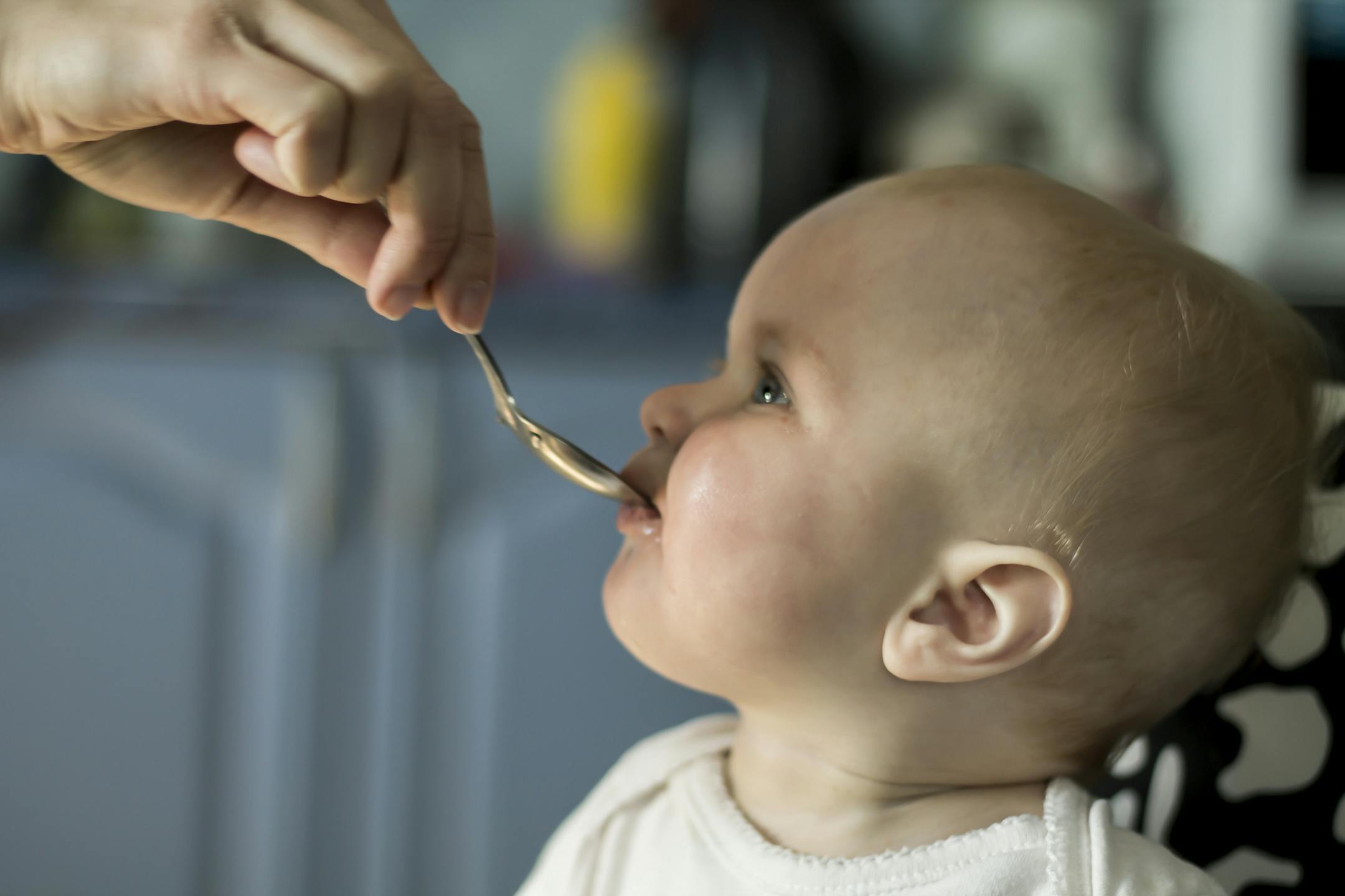 Profile shot of little baby taking medicine from the spoon in mothers hand.istock photo