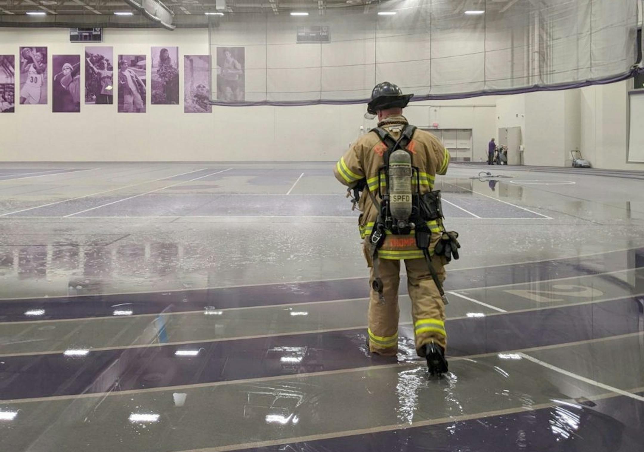 A firefighter walked through the flooded Anderson Athletic Center field house on Monday, Feb. 10. A softball hit and broke a sprinkler, causing the flood Monday evening.