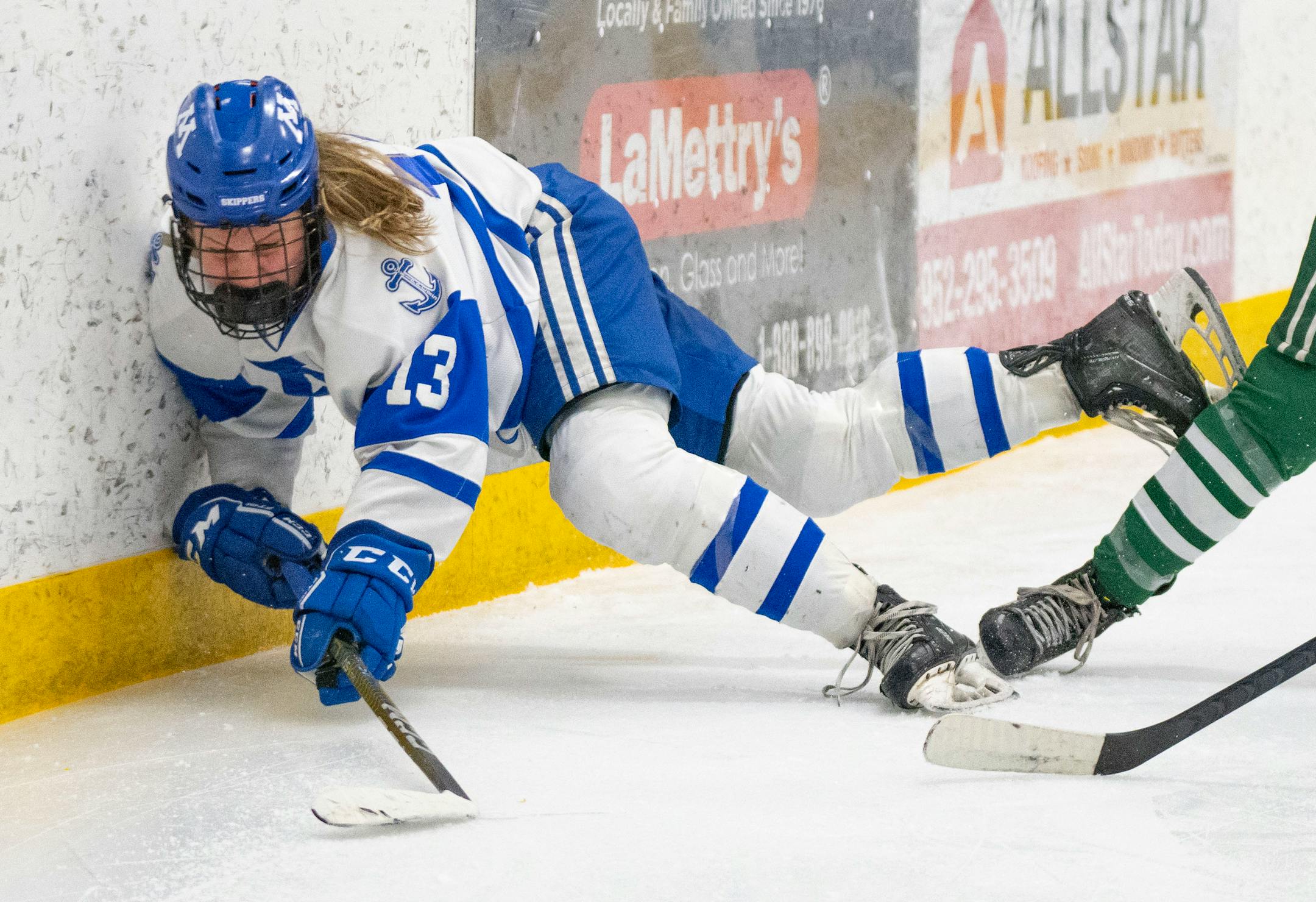 Minnetonka forward Lindzi Avar (13) falls against the boards as she tries to control the puck against Holy Family in the third period.