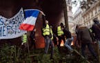 A demonstrator wearing a yellow jacket waves a French flag near the Champs-Elysees avenue during a demonstration Saturday, Dec. 1, 2018, in Paris. Fre