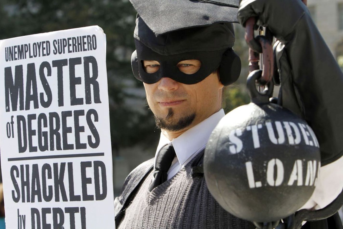 FILE - In this Oct. 6, 2011 file photo, Gan Golan, of Los Angeles, dressed as the "Master of Degree," holds a ball and chain representing his college loan debt, as several groups including the Peoples Uprisings, October2011 Coalition, and Occupy DC, "occupy" Freedom Plaza in Washington. Having started in New York, demonstrations now take place all across the United States, as protesters are speaking out against corporate greed and the gap between the rich and the poor.