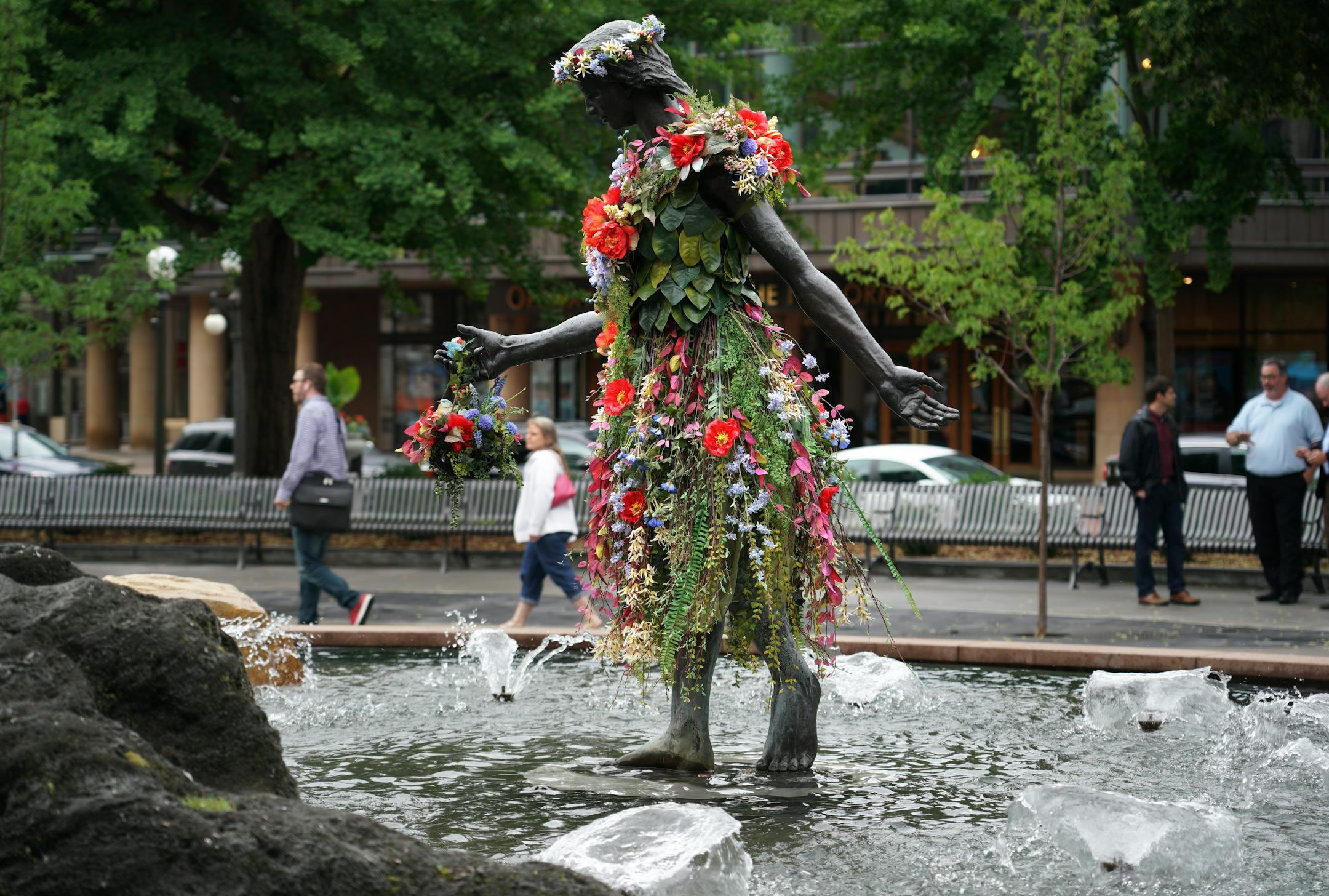 A remade version of St. Paul's historic Rice Park was unveiled at a ceremony Tuesday afternoon. The new park modifications include a more open design with entry corners with seat walls, raised garden beds by the St. Paul Garden Club and a central space for events and gatherings. Here, the girl in the fountain remains and was decked out in flowers Tuesday afternoon.]