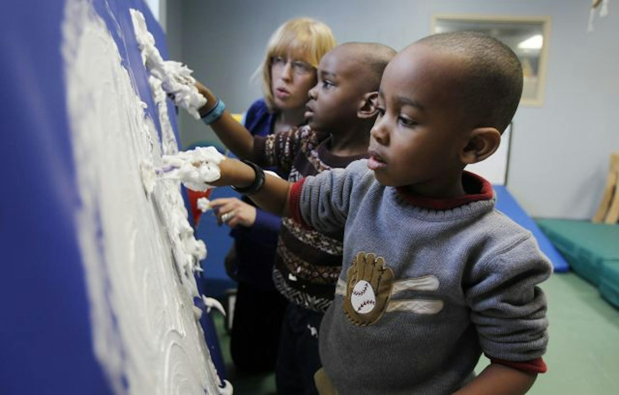 Elisa Roiko right a therapist helps twins Elijah (middle) and Seth 4, Fernandez as they worked with shaving cream. The cream helps the children with sensitivity.