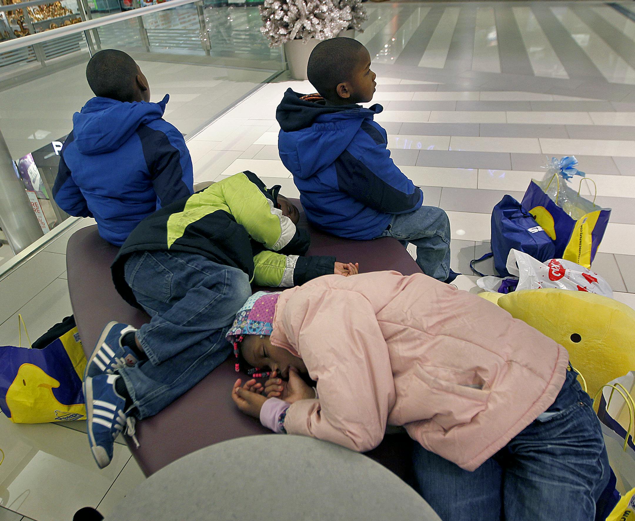 After an all-night shopping adventure, Myron Harris, 9, from left, and his siblings Mason, 6, Marion, 7, (green) and Maketia Harris, 8, (pink) found a place to rest and sleep at the Mall of America, Friday, November 29, 2013. Their mother Dede Harris said she was able to get a lot of shopping done overnight. (ELIZABETH FLORES/STAR TRIBUNE) ELIZABETH FLORES • eflores@startribune.com