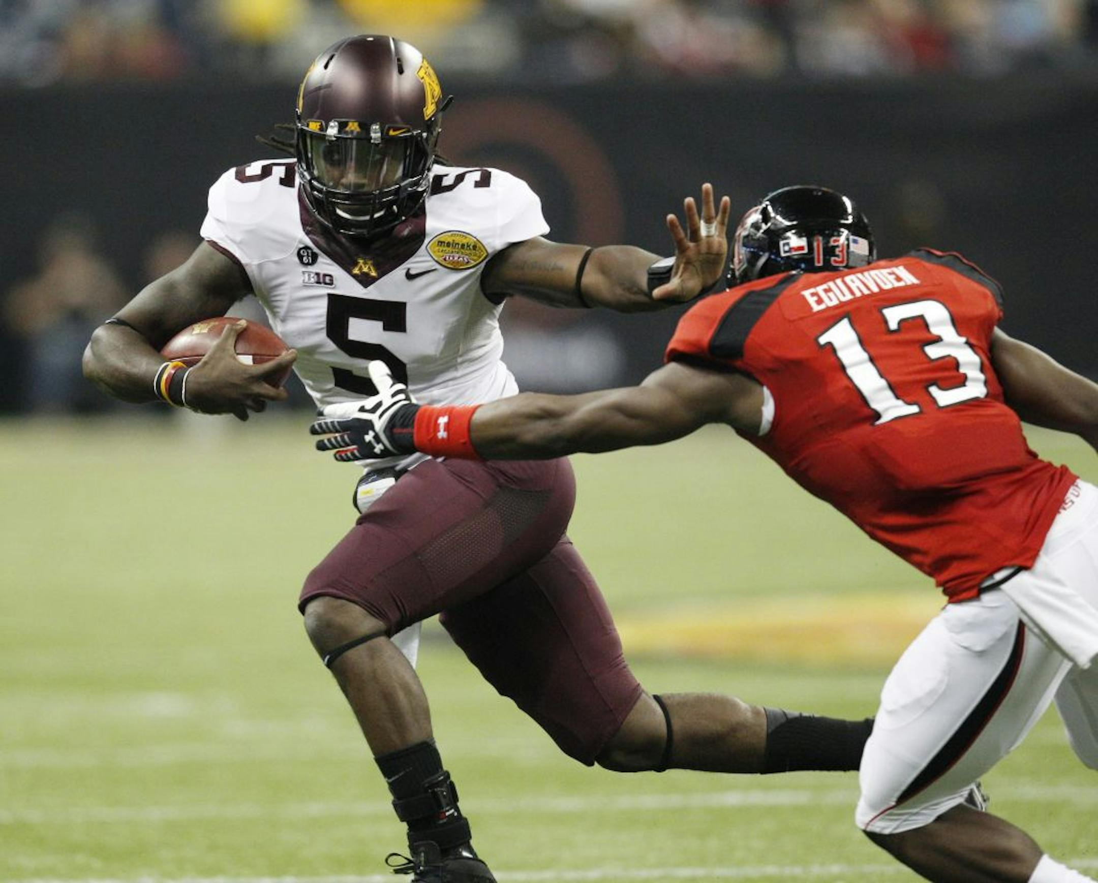 Minnesota quarterback MarQueis Gray stiff-arms Texas Tech's Sam Eguavoen in the Meineke Car Care Bowl of Texas.