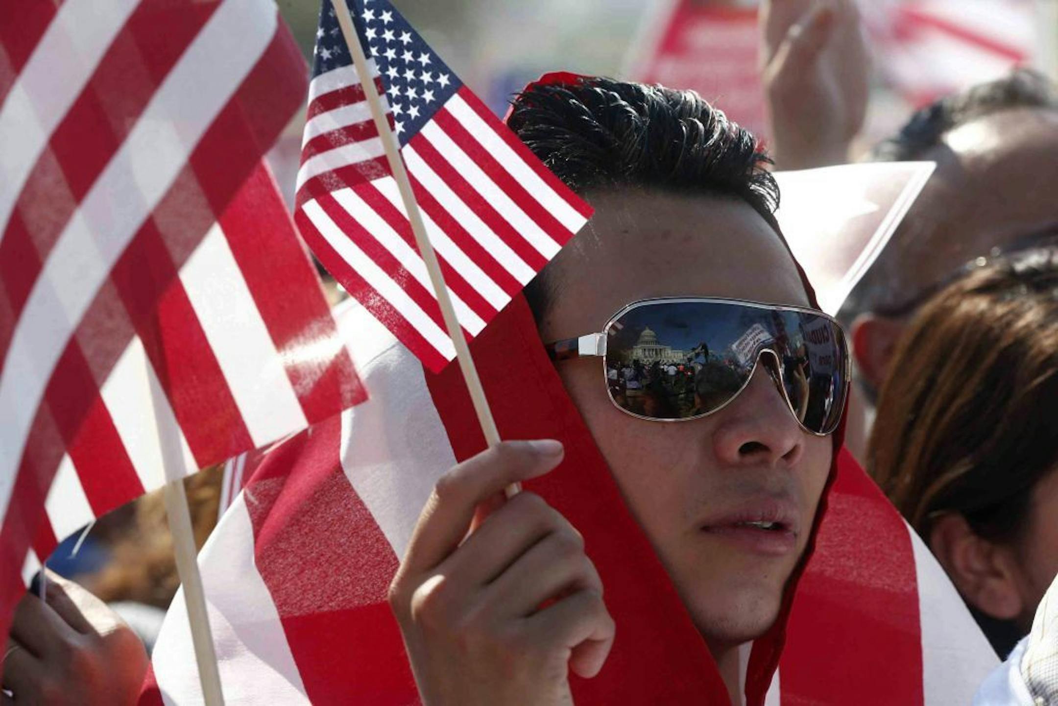 Edward Gonzales from Herndon, Va., whose family is from El Salvador, shields himself from the sun with a U.S. flag, as he participates in a rally for immigration reform on Capitol Hill in Washington, Wednesday, April 10, 2013.