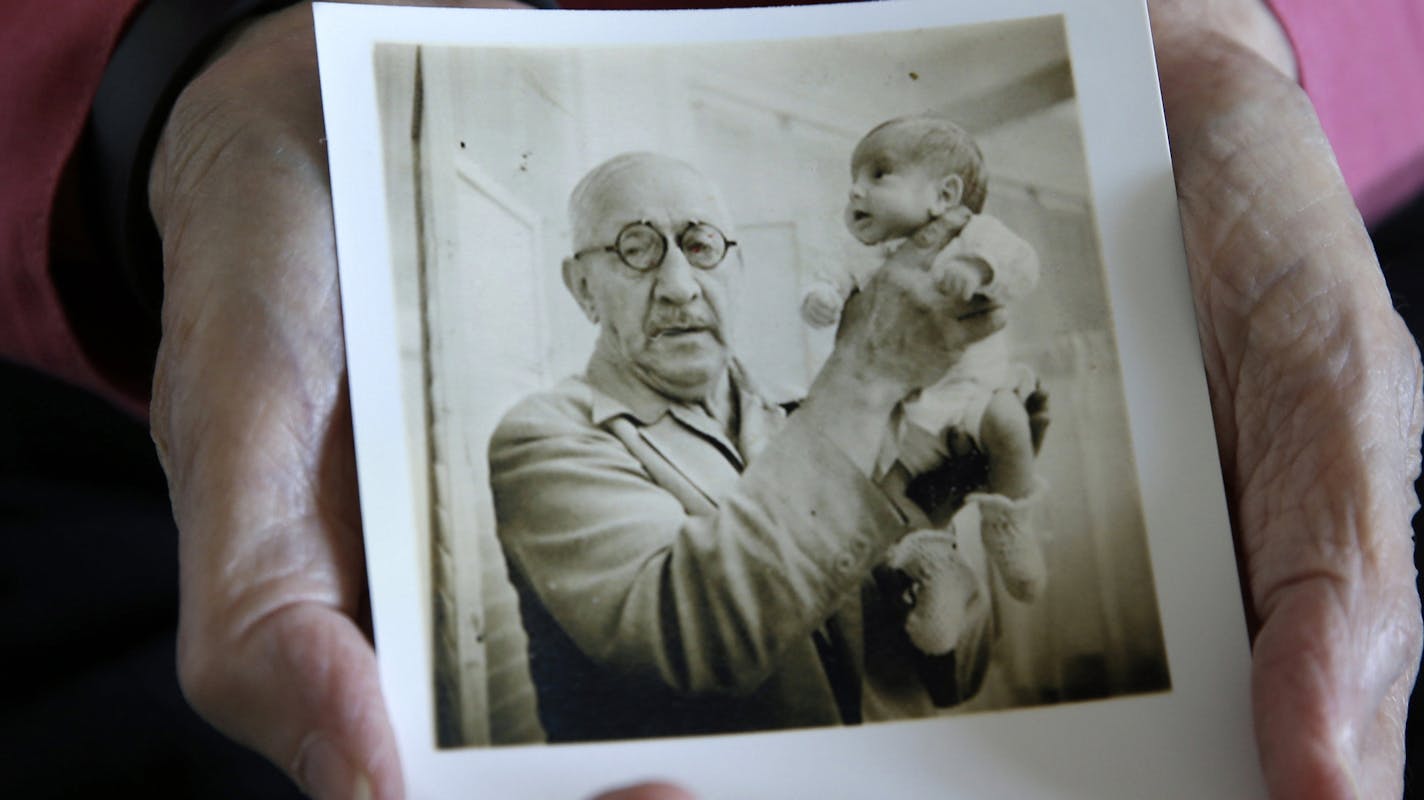 In this photo taken Thursday, July 23, 2015, Beth Allen holds a photograph taken by her father that shows her being held by Dr. Martin Couney at his Coney Island incubator sideshow, where she was on display with others after she was born premature in 1941, at her home in Hackensack, N.J. A century before reality TV, premature infants were put on display in primitive incubators. People paid 25 cents to see them at world's fairs, on the Atlantic City boardwalk, the sideshows at Coney Island and el