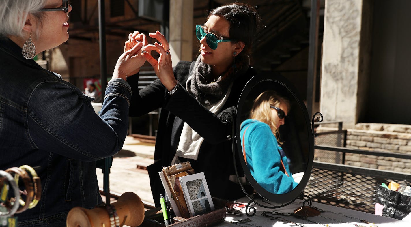 Jewelry maker Chris Chookiatsirichai, center, showed off a piece at her stand, Tribal Delightful Concoctions, in the Mill City Farmer&#x2019;s Market.