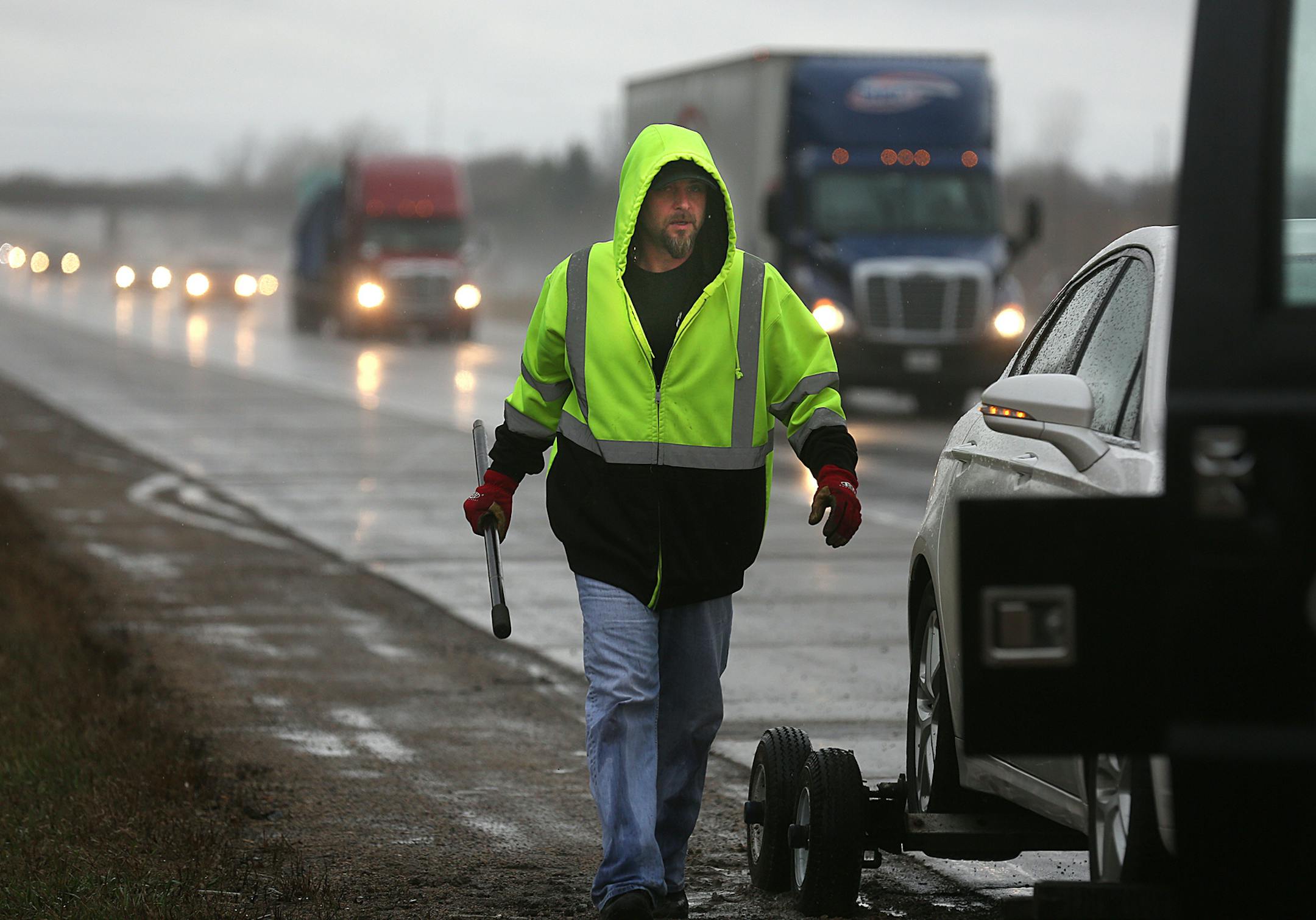 Tow truck owner Tim Heldman walked along the Interstate 94 shoulder after preparing to tow a car with a flat tire near Woodbury.