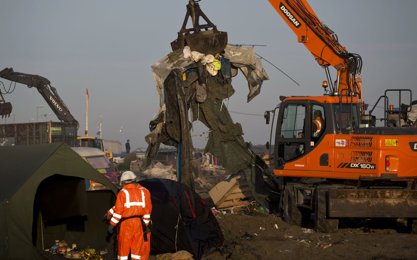 Mechanical diggers work to clean up a makeshift migrant camp known as "the jungle" near Calais, northern France, Thursday, Oct. 27, 2016. French authorities claimed on Wednesday that they had cleared the makeshift migrant camp near the northern French city of Calais. (AP Photo/Emilio Morenatti) ORG XMIT: EM101