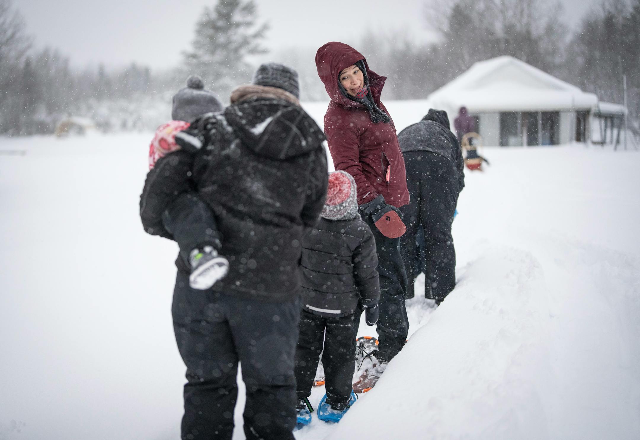 Niizhwaasangookwe Miigis Gonzalez looksedbackwards to talk to her son as she walks in snowshoes to check on rabbit snares as part of the Ojibwe immersion program on Wednesday, Jan. 4, 2023 at in Cloquet, Minn.The Ojibwe immersion program is offered through the Fond du Lac Tribal and Community College in Cloquet and is the first of its kind in Minnesota. Babies up to age 5 attend with a parent to be fully immersed in the Ojibwe language, all while practicing traditional Anishinaabe activities like snaring rabbits.