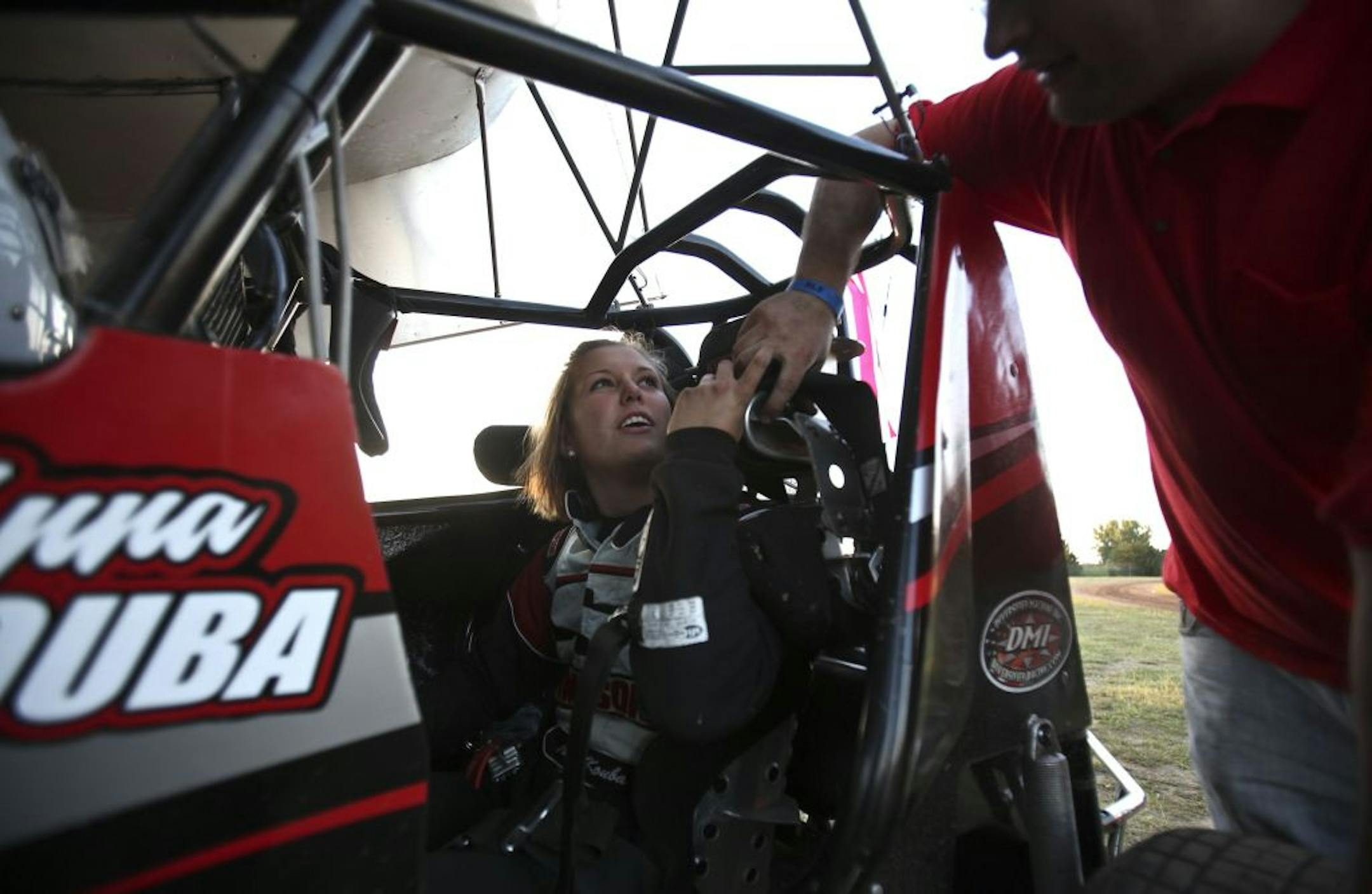 Sprint car racer Anna Kouba , 19, of Lino Lakes, received some help from crew member Keith Hodnefield strapping into her car before the start of her heat at the dirt track in Princeton, Minn., on June 25.