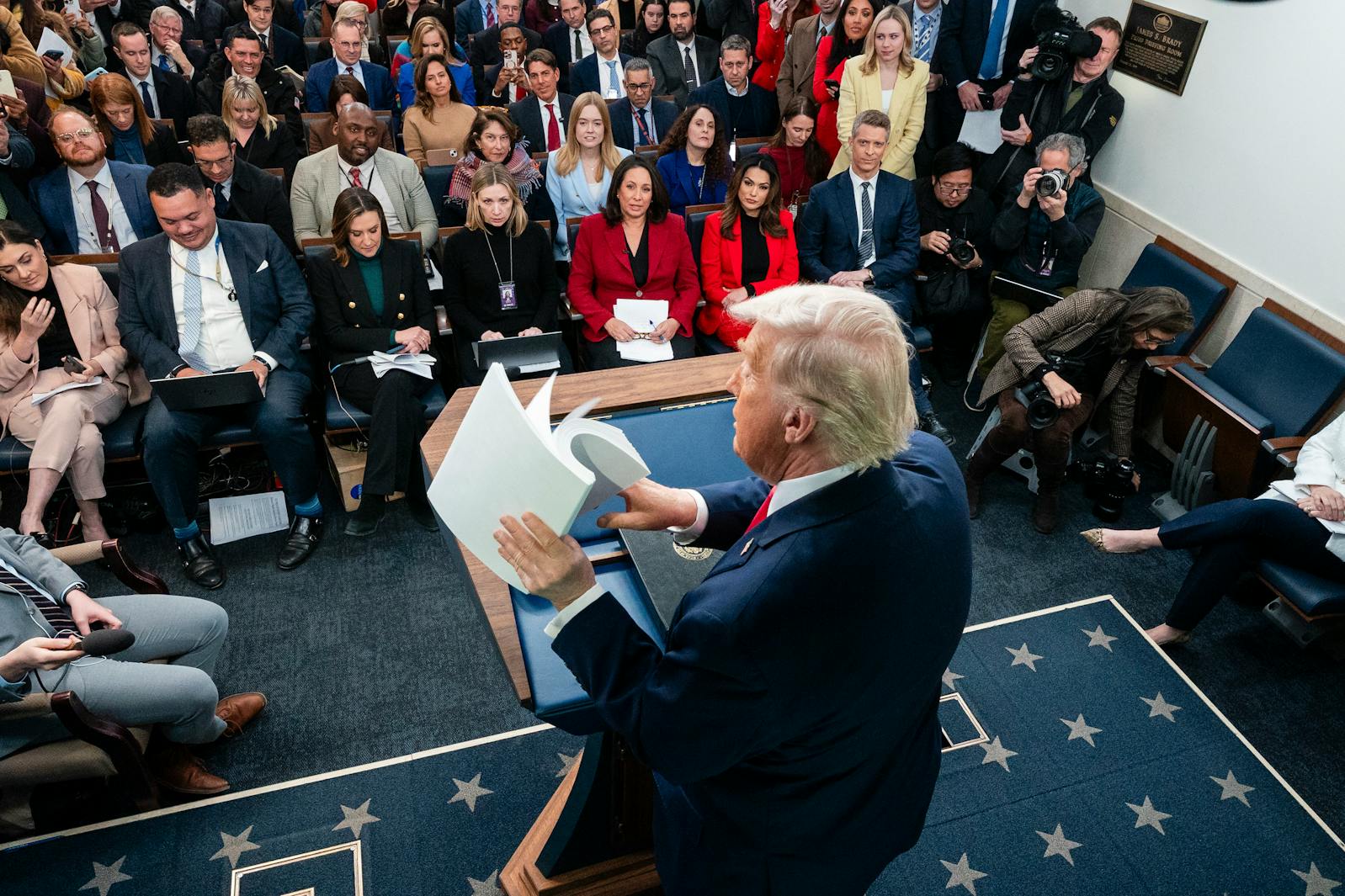 President Donald Trump holds a packet of papers labeled “accomplishments” while speaking to reporters at the White House on Jan. 20. 