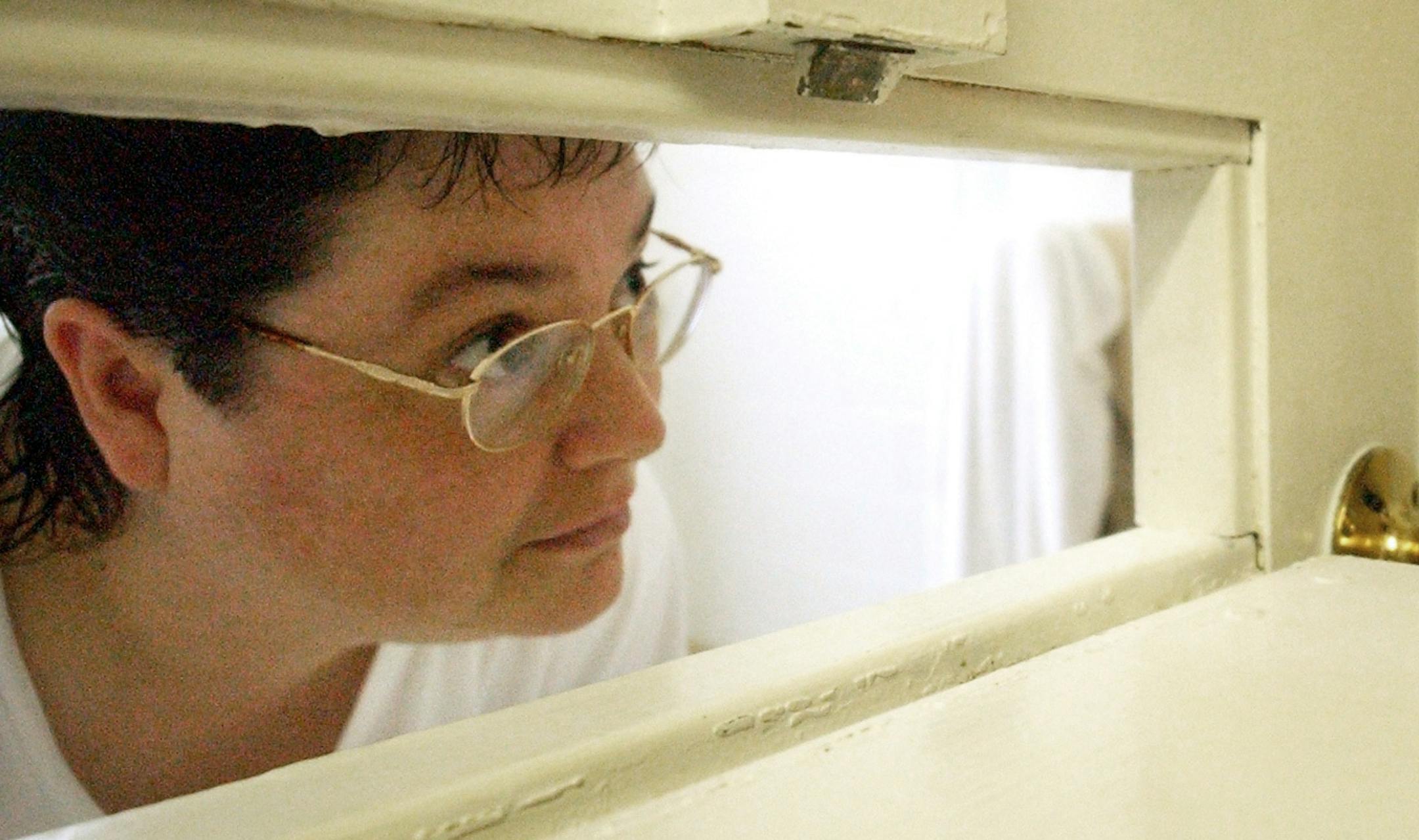 FILE - In this Tuesday, July 6, 2004, file photo, Kelly Gissendaner, the only woman on Georgia's death row, peers through the slot in her cell door as a guard brings her a cup of ice at Metro State Prison in Atlanta. Gissendaner is scheduled to be executed Sept. 29, 2015, more than six months after her previously scheduled execution was called off at the last minute because of a problem with the lethal execution drugs. (Bita Honarvar/Atlanta Journal-Constitution via AP, File)