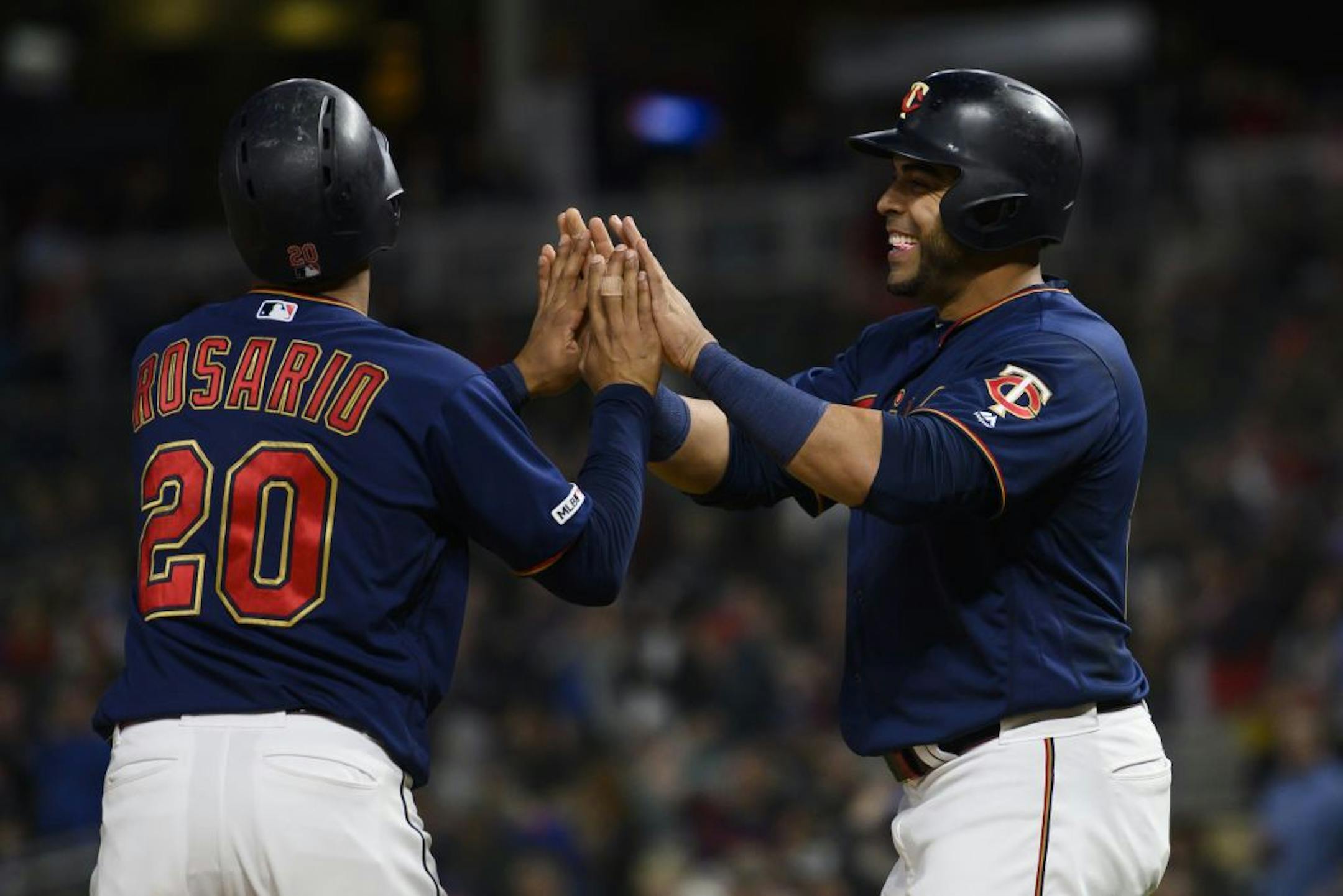 Minnesota Twins left fielder Eddie Rosario (20) and designated hitter Nelson Cruz (23) celebrated after scoring runs off a home run hit by first baseman C.J. Cron (24) in the bottom of the fifth inning.
