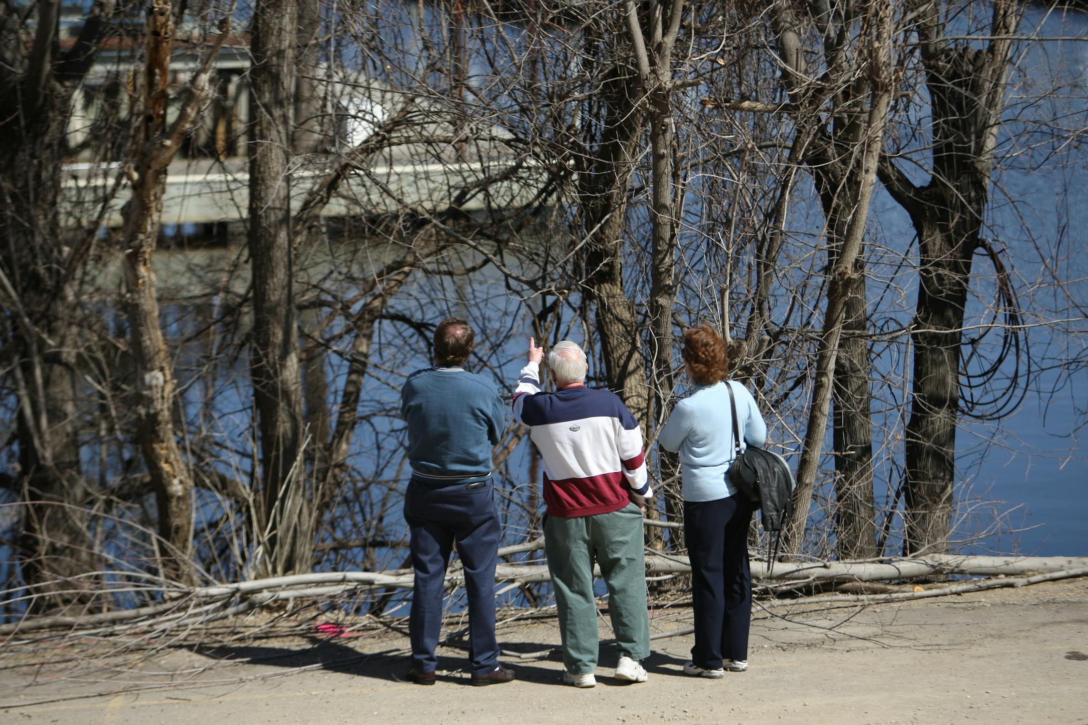 Bernie Peltier pointed out the path of the car through the trees on the bank of the St. Croix River in Stillwater. At left is Doug Hesley, who lives near the site. The woman at right is unidentified.