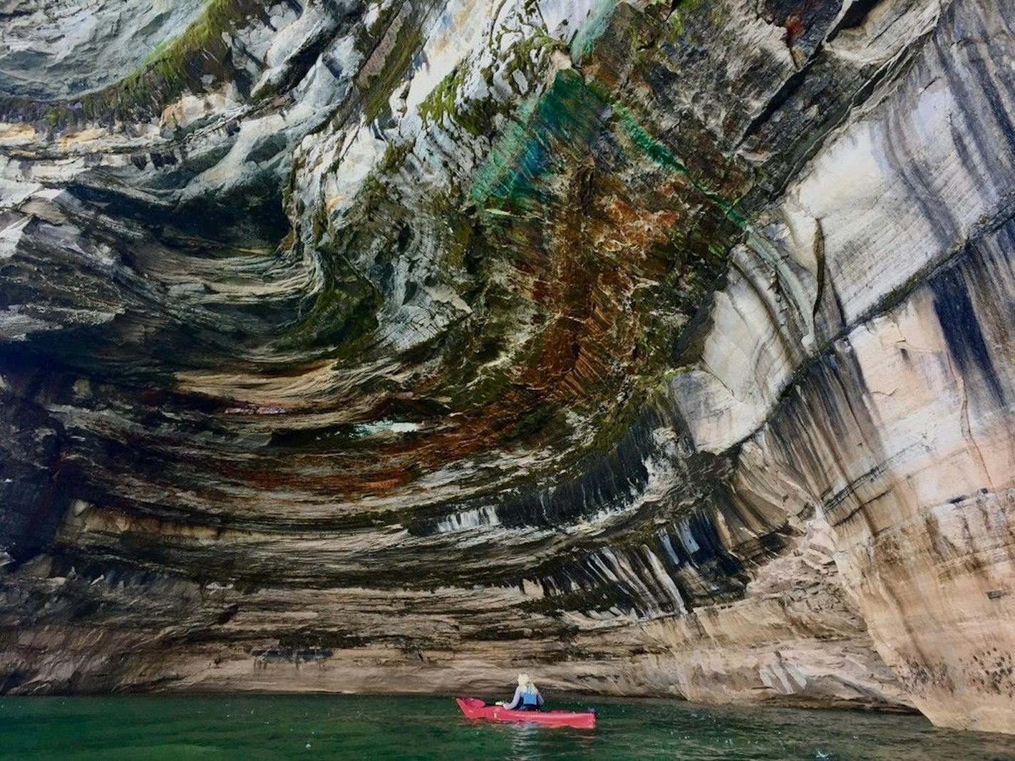 This file photo from Aug. 1, 2018 shows the scale of the cliffs along Pictured Rocks National Lakeshore in Michigan, along the south shore of Lake Superior, as a kayaker paddled by.