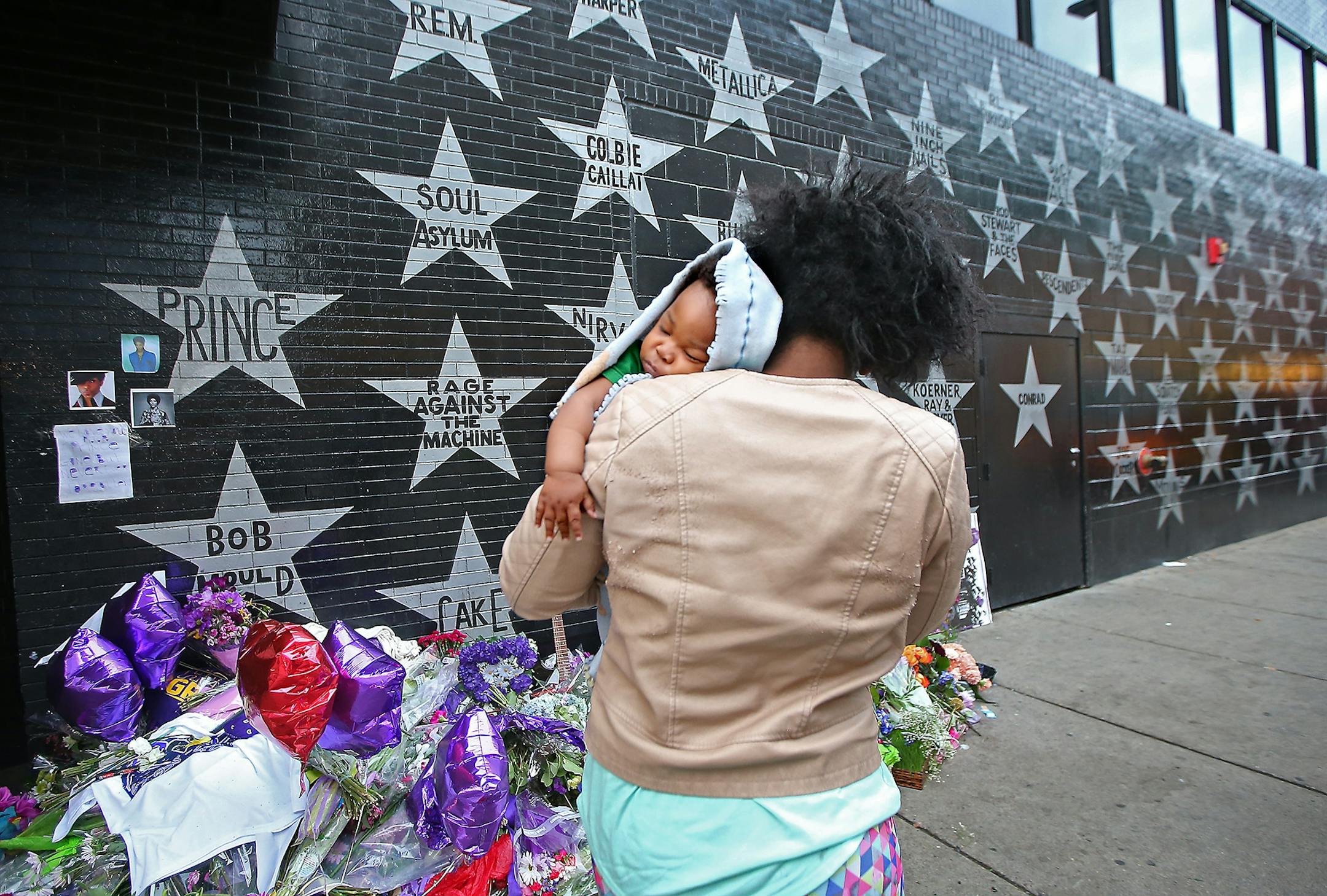 Shanika Haynes, cq, took a moment to grab a photo of the Prince star and memorials as she carried her sleeping baby King Haynes, 7-months, outside First Avenue, Friday, April 22, 2016 in Minneapolis, MN.