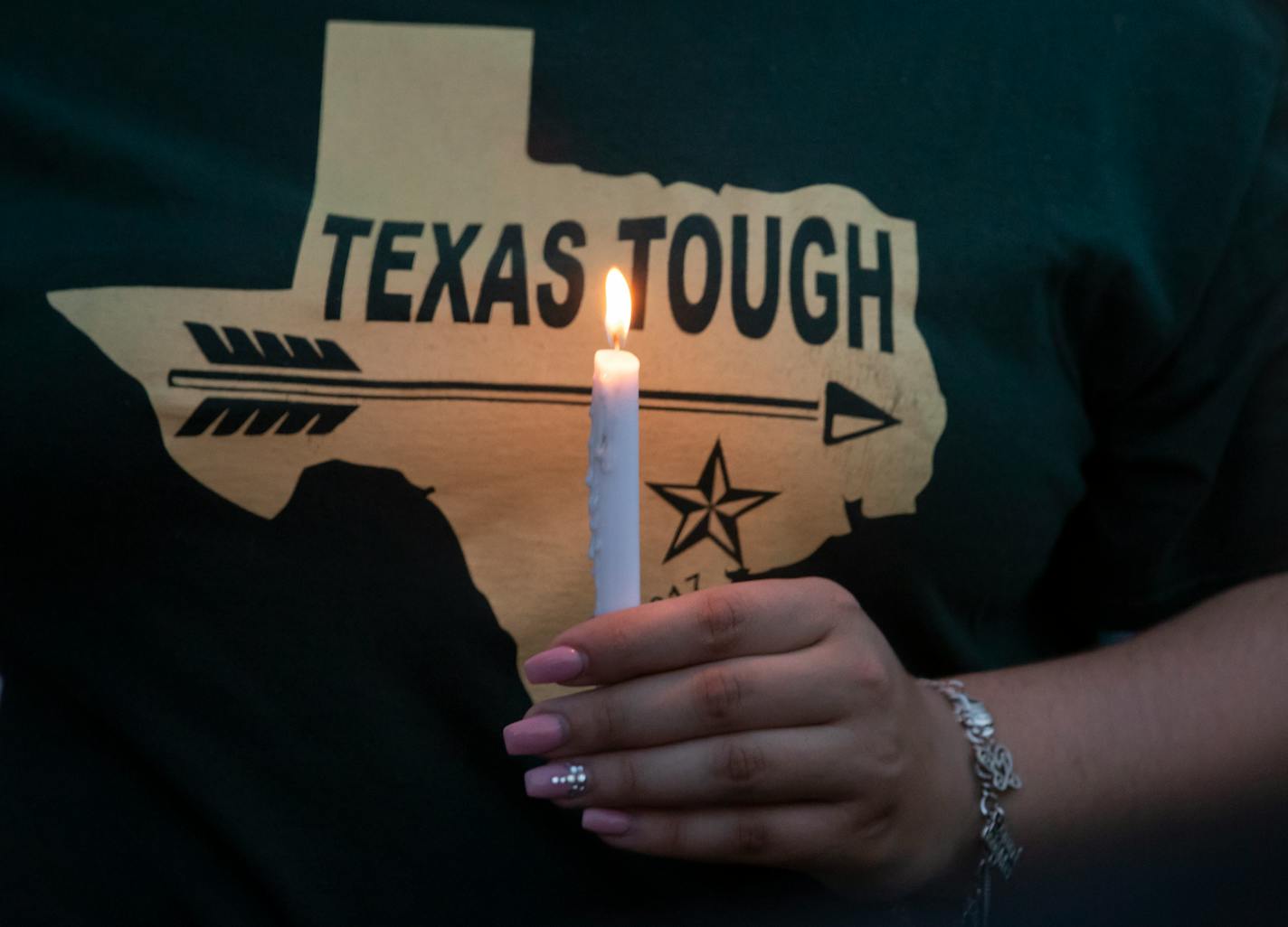 A woman wearing a Texas T-shirt held a candle during a vigil in the wake of a deadly school shooting at Santa Fe High School on Friday in Galveston, Texas.