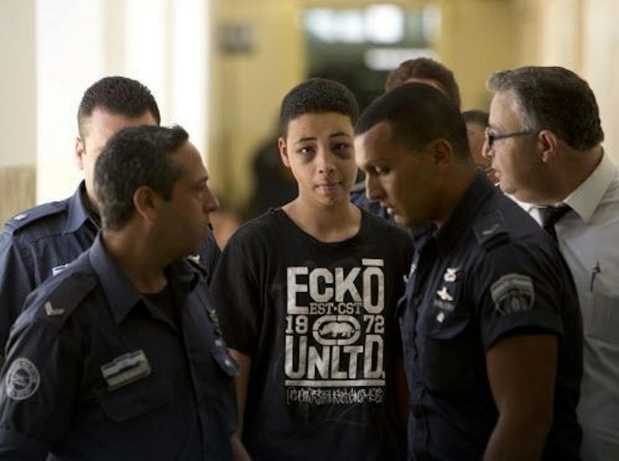 Tariq Abu Khdeir, 15, a U.S. citizen who relatives say was beaten and arrested by Israeli police during clashes sparked by the killing Thursday of his cousin Mohammed Abu Khdeir, is escorted by Israeli prison guards during an appearance at Jerusalem magistrate's court Sunday, July 6, 2014.