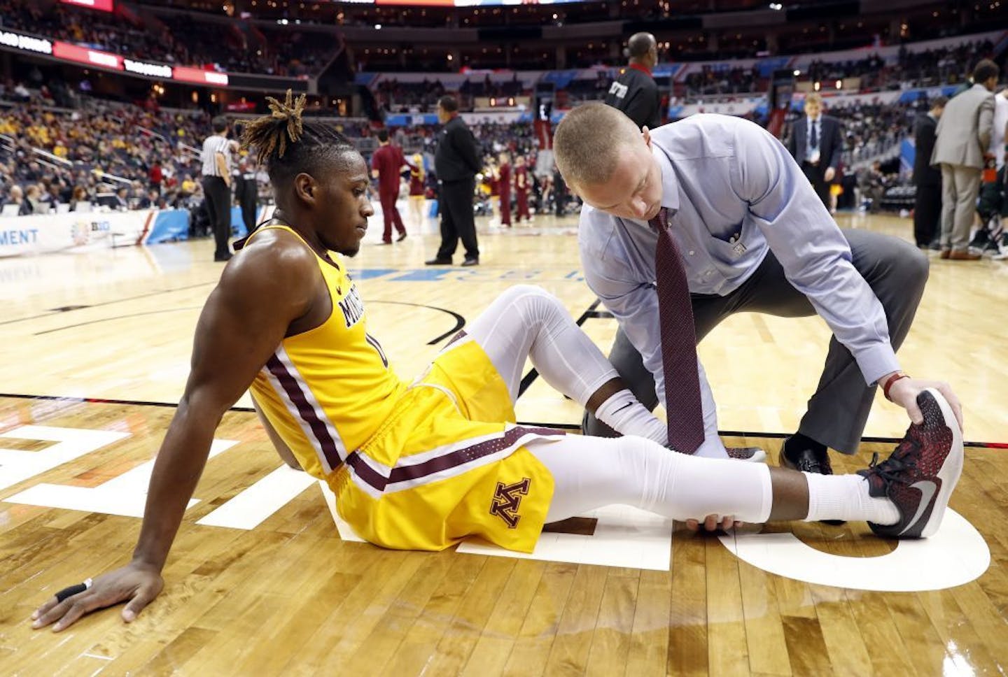 Minnesota guard Akeem Springs (0) is checked by a trainer after an injury during the second half of an NCAA college basketball game against Michigan State in the Big Ten tournament, Friday, March 10, 2017, in Washington. Springs did not return to the game.