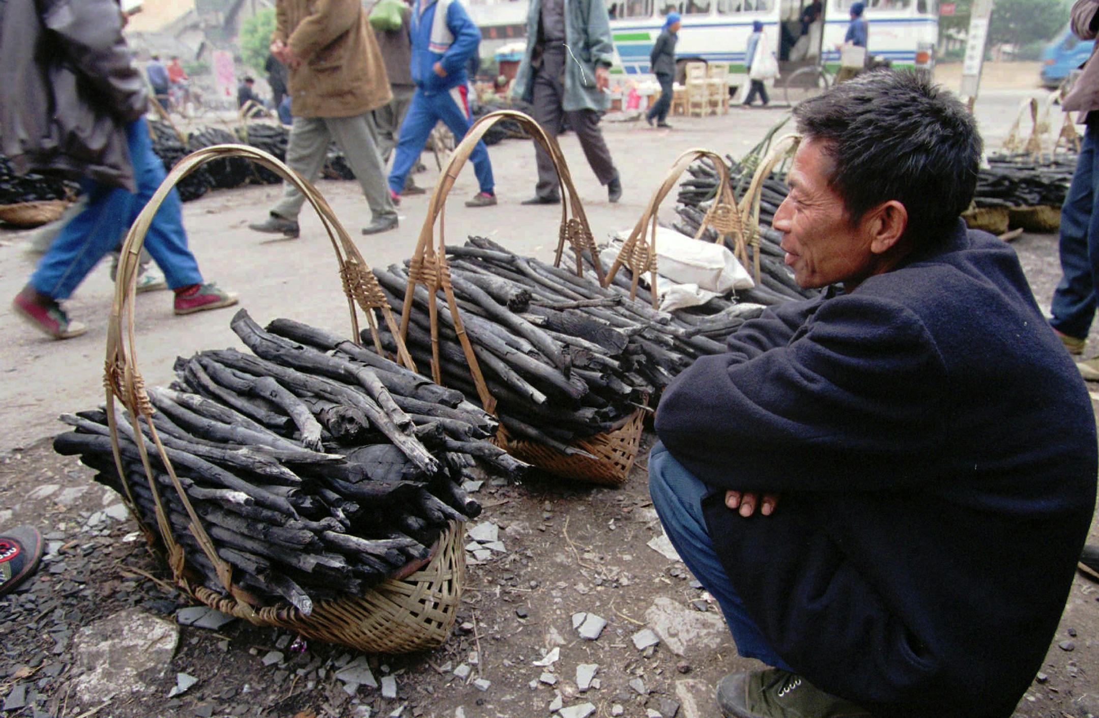 A Chinese man waits for customers for his baskets of charcoal at a busy street market in Yingshan, near Guilin, in south China's Guangxi province Thursday, Jamuary 16, 1996. Farmers in the area supplement their incomes by collecting charcoal in the mountains and selling it for heating and cooking in nearby towns. (AP Photo/Greg Baker) ORG XMIT: BEJ103