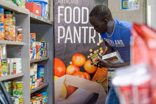 Oballa Oballa stocks the shelves at a food pantry for students at Riverland Community College in Owatonna.