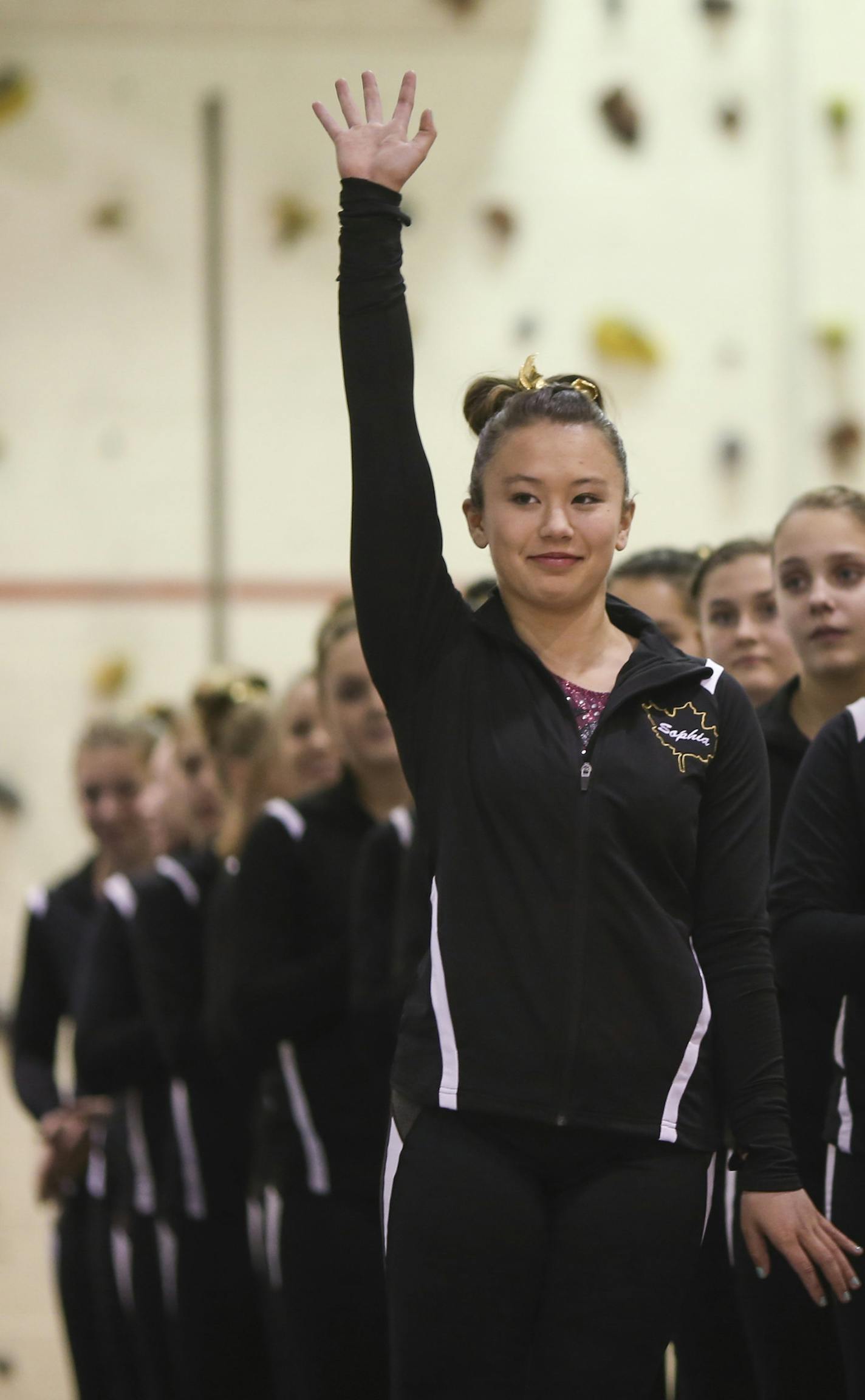 Sophia Thompson waved as she was introduced along with her Maple Grove teammates before the meet began Tuesday night. ] JEFF WHEELER &#xef; jeff.wheeler@startribune.com Maple Grove senior gymnast Sophia Thompson reluctantly moved with her family to Maple Grove from North Dakota. After major surgery on both knees she has come out of retirement to finish her career with Maple Grove. She competed on the uneven bars in a meet against Coon Rapids Tuesday night, December 1, 2015 at Maple Grove.