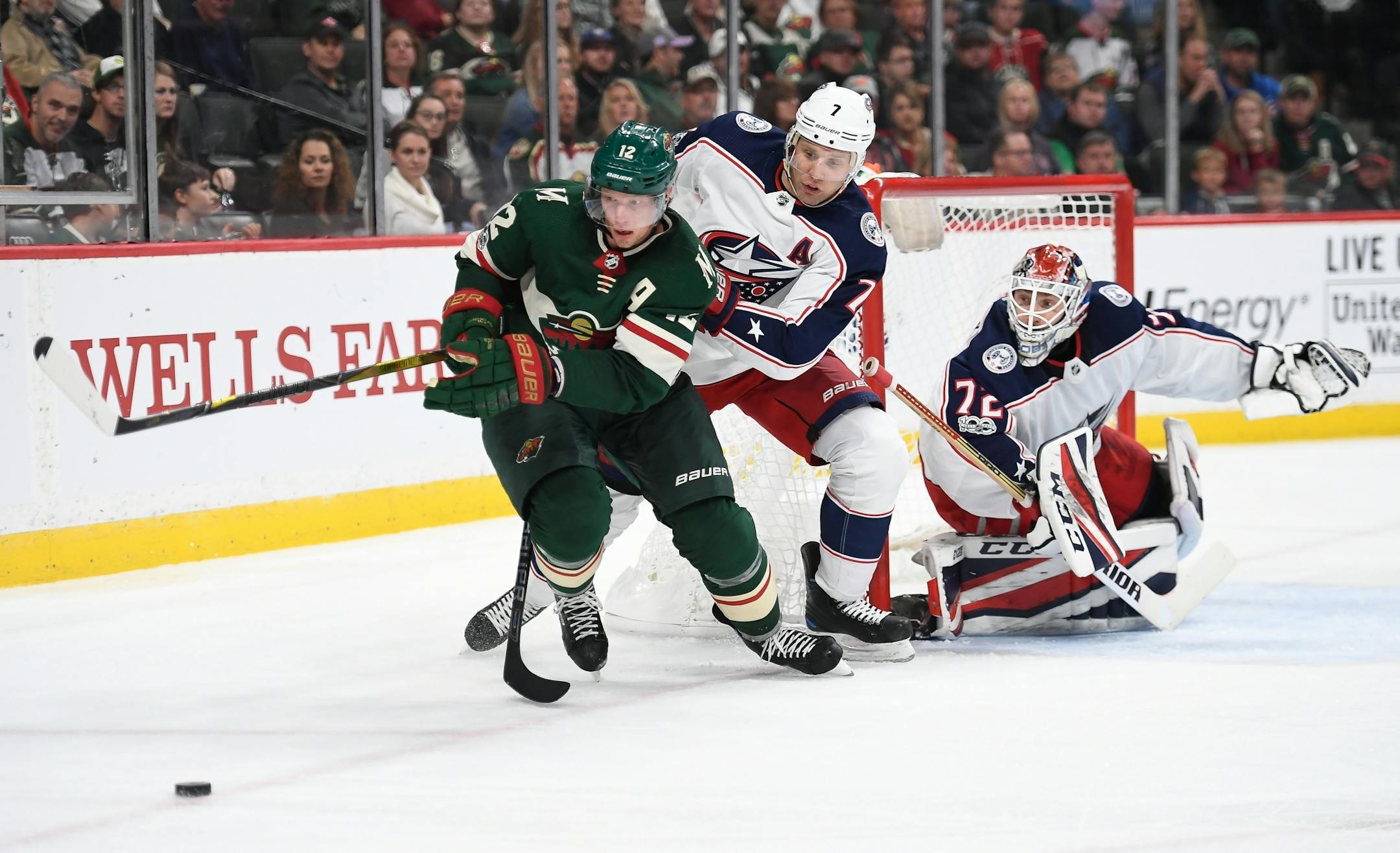 Minnesota Wild center Eric Staal (12) tried to control a rebounded shot while being challenged from behind by Columbus Blue Jackets defenseman Jack Johnson (7) in the third period.