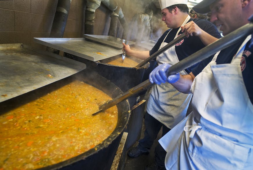 At Casey Lake Park in North St. Paul where the fire department held its annual booya fundraiser, Bill Weber whose great grandfather created the recipe in 1927 stirs one of the cooking pots containing over 500 gallons of the stew. In the foreground is Jeff Ernewein who got his part-time job interviewing at last year's booya event.