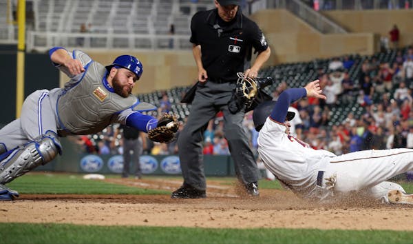 Minnesota Twins' Joe Mauer, right, beats the tag attempt by Toronto Blue Jays catcher Russell Martin to score on a Max Kepler double in the seventh in