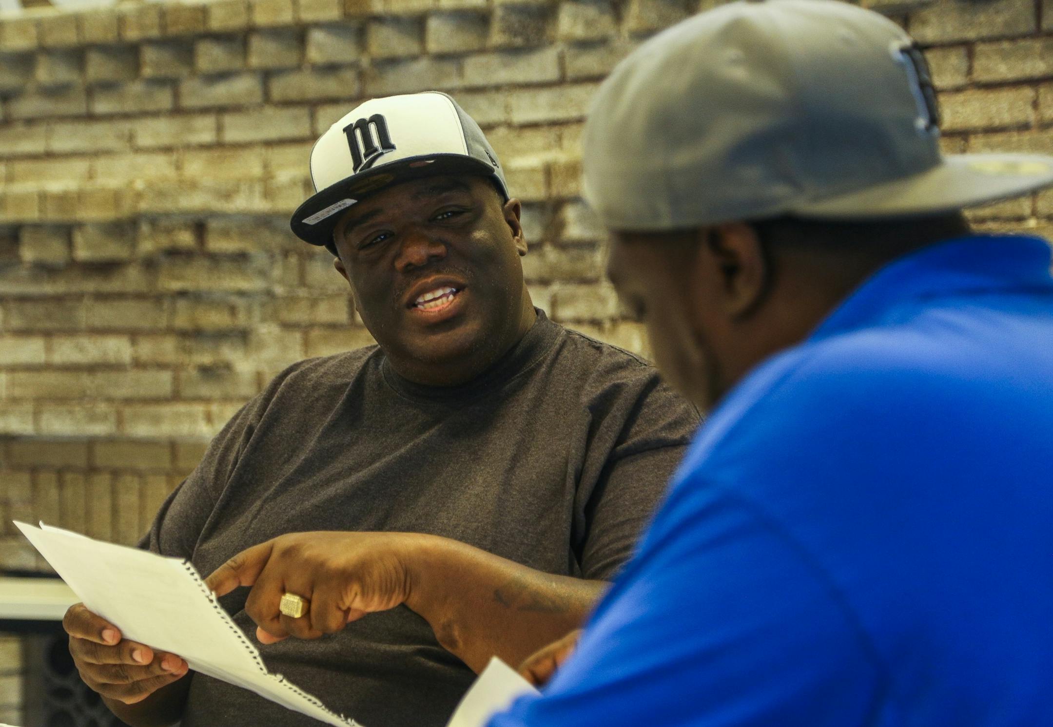 Ferome takes a look at reflection letters written by New Day mentors-in-training with Urban Youth Conservation co-founder Will Wallace, right, at EMERGE Community Development on June 30, 2016. For the last assignment, the mentors-in-training had to find a young person in the community to mentor and interview them as a way to find out what aspects of their neighborhood need improvement.