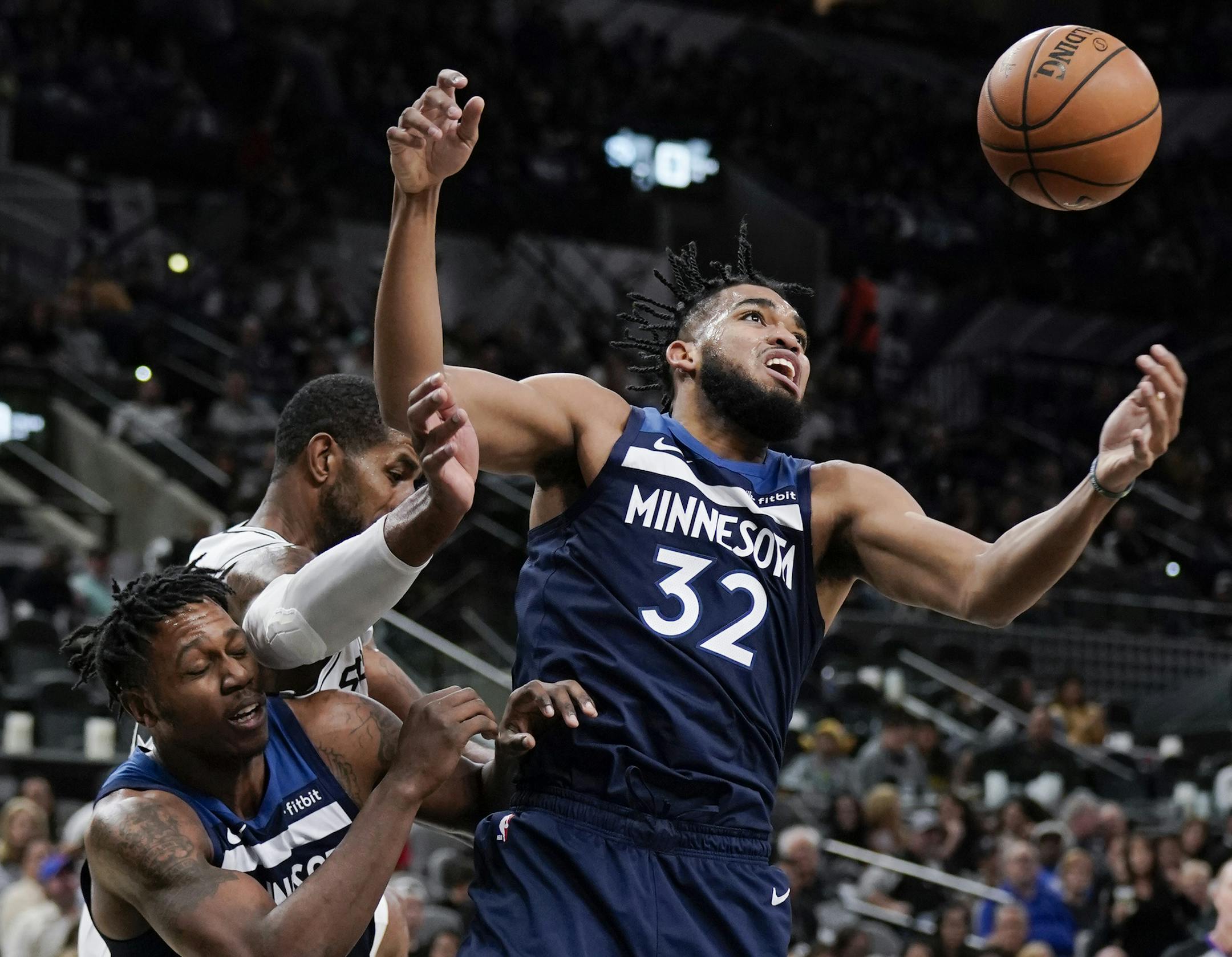 Minnesota Timberwolves' Karl-Anthony Towns (32) and Treveon Graham, left, fight for possession against San Antonio Spurs' LaMarcus Aldridge during the second half of an NBA basketball game Wednesday, Nov. 27, 2019, in San Antonio. Minnesota won 113-101. (AP Photo/Darren Abate)