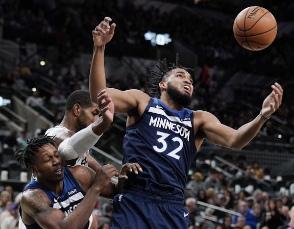 Minnesota Timberwolves' Karl-Anthony Towns (32) and Treveon Graham, left, fight for possession against San Antonio Spurs' LaMarcus Aldridge during the