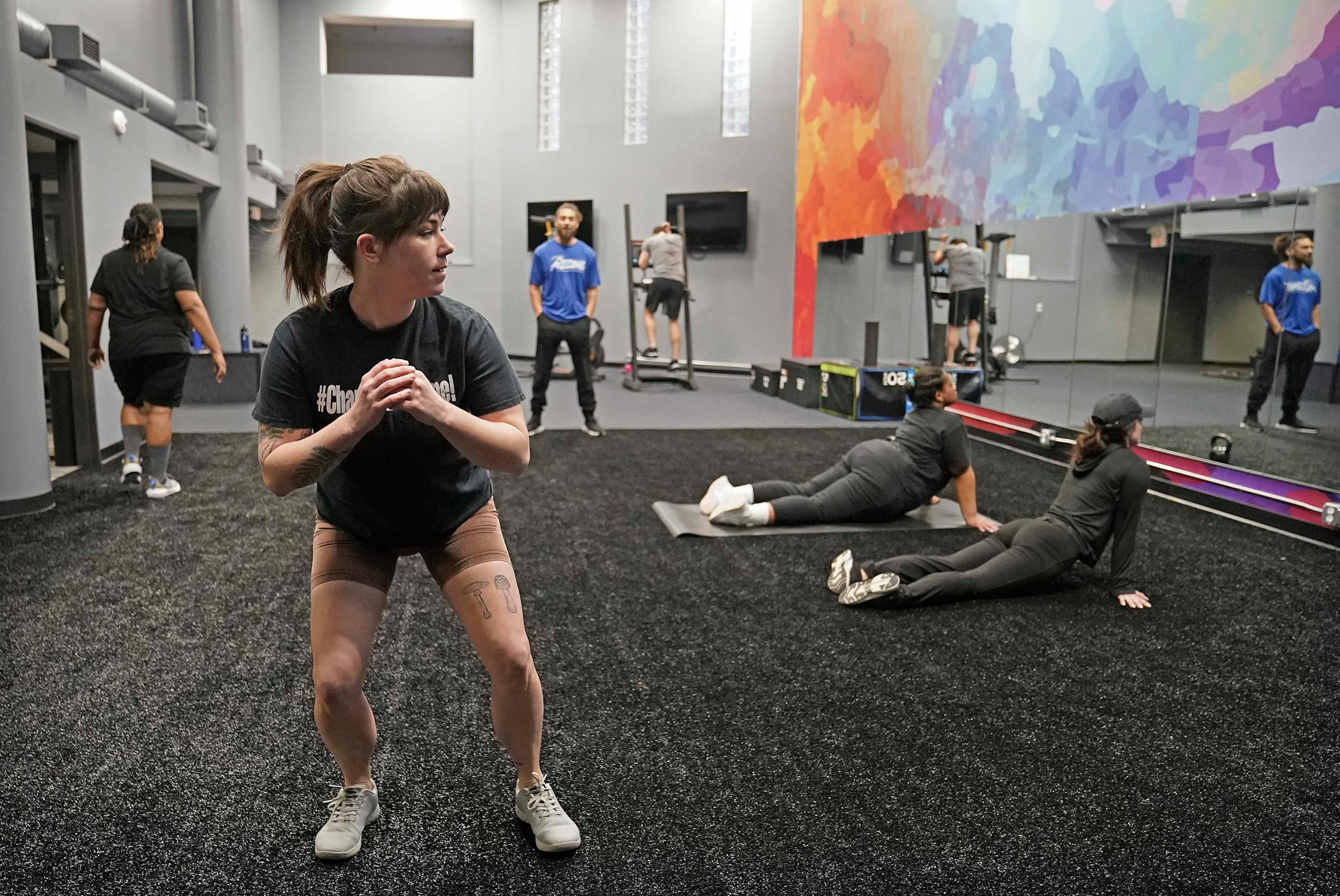 Laura Bremseth, front, works out at the Totally Committed Resource Center fitness center Friday, Feb. 24, 2023, in Minneapolis, Minn. Owner Tyler Phillips describes Totally Committed Resource Center as "a one-stop shop for health and wellness."